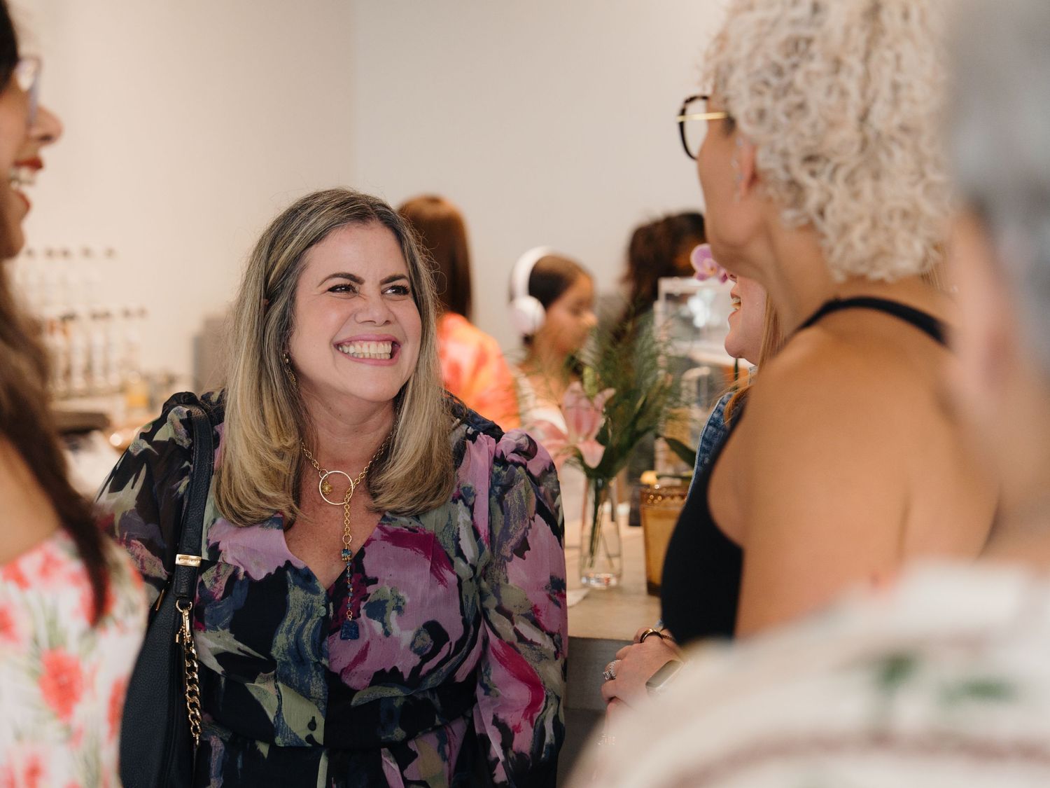 Women socializing and smiling at an indoor networking event in a bright, modern space.