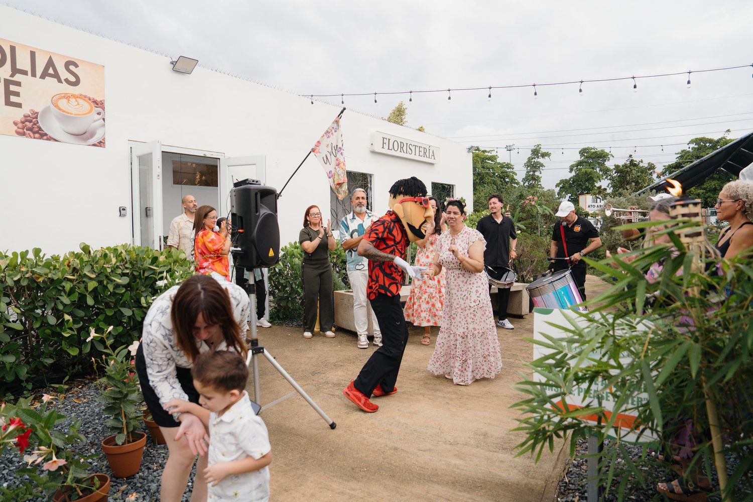 Lively outdoor garden party with guests dancing and a band performing near a white building.