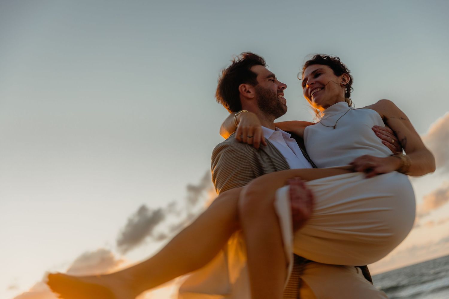 Romantic couple silhouetted against a sunset sky during an intimate moment.