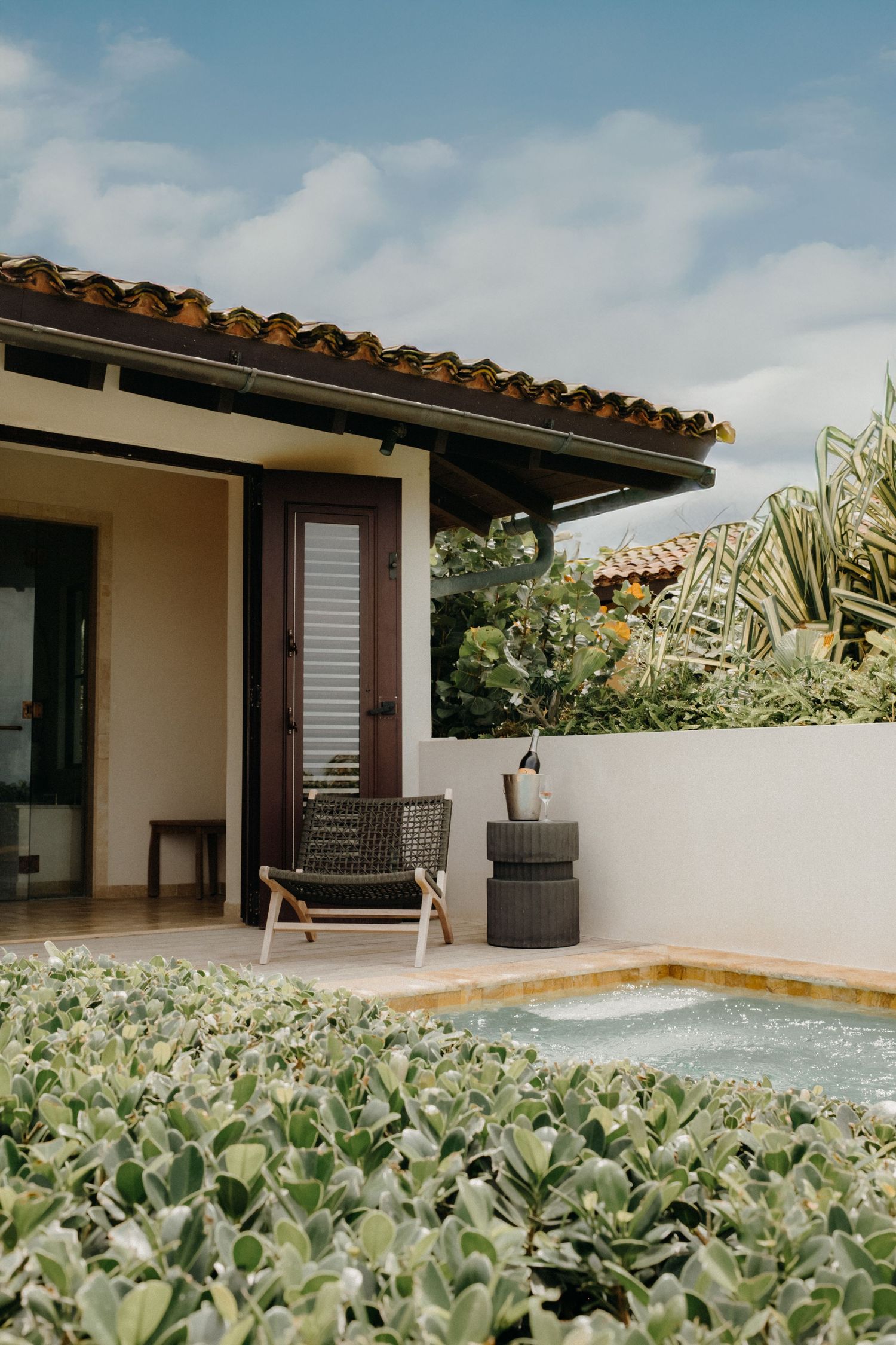 Modern villa patio with swimming pool and lush tropical landscaping.