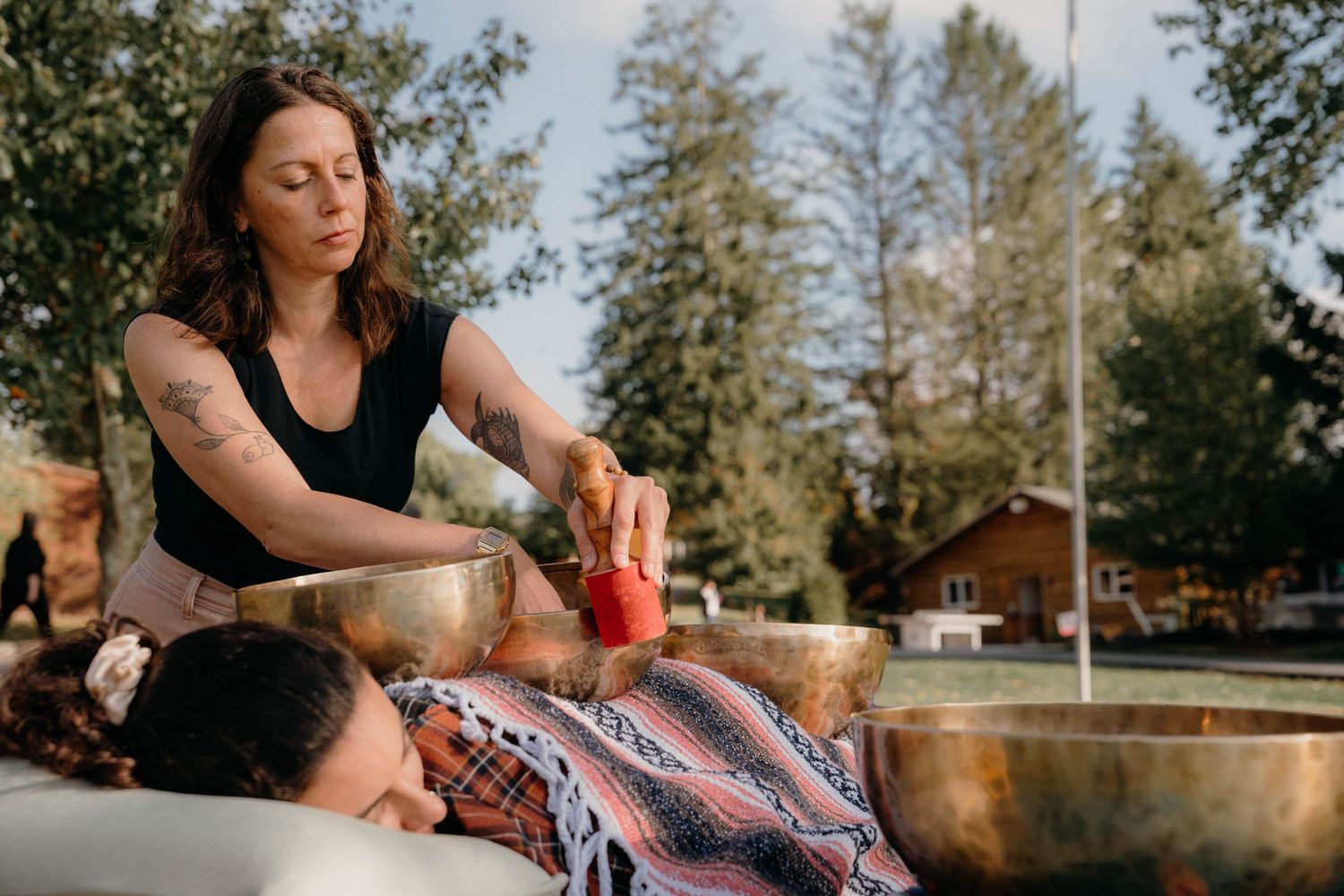 A therapeutic massage session taking place outdoors with trees in the background.