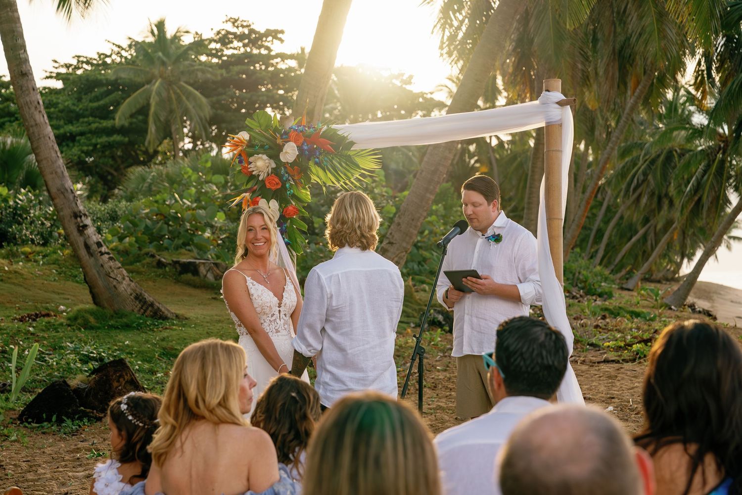 Outdoor garden party setting with string lights and palm trees at sunset.