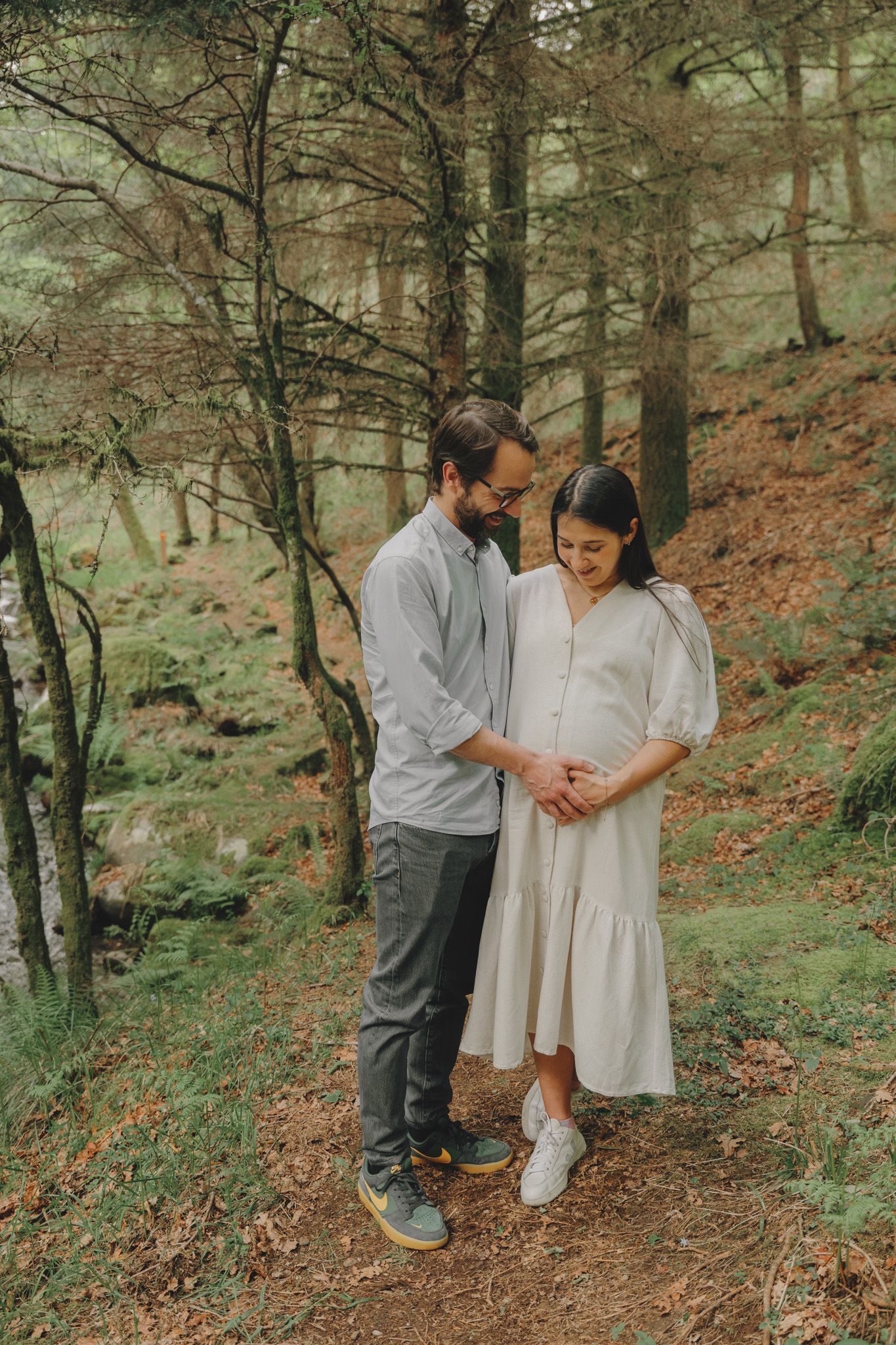 Couple shares an intimate moment on a forest trail surrounded by lush greenery.
