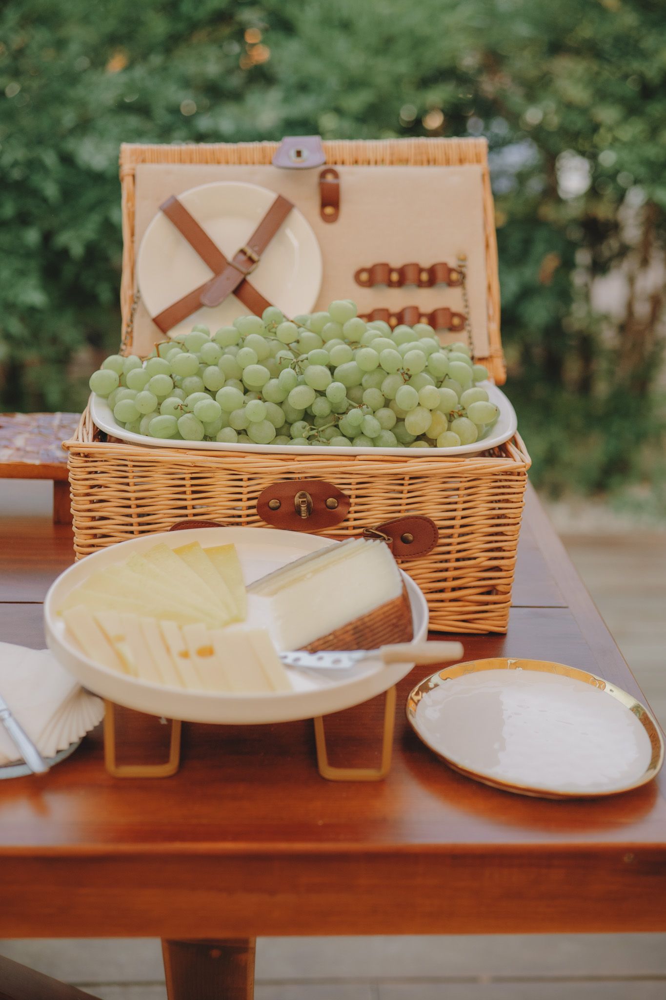 Fresh green grapes and cheese plates arranged on a wooden table.