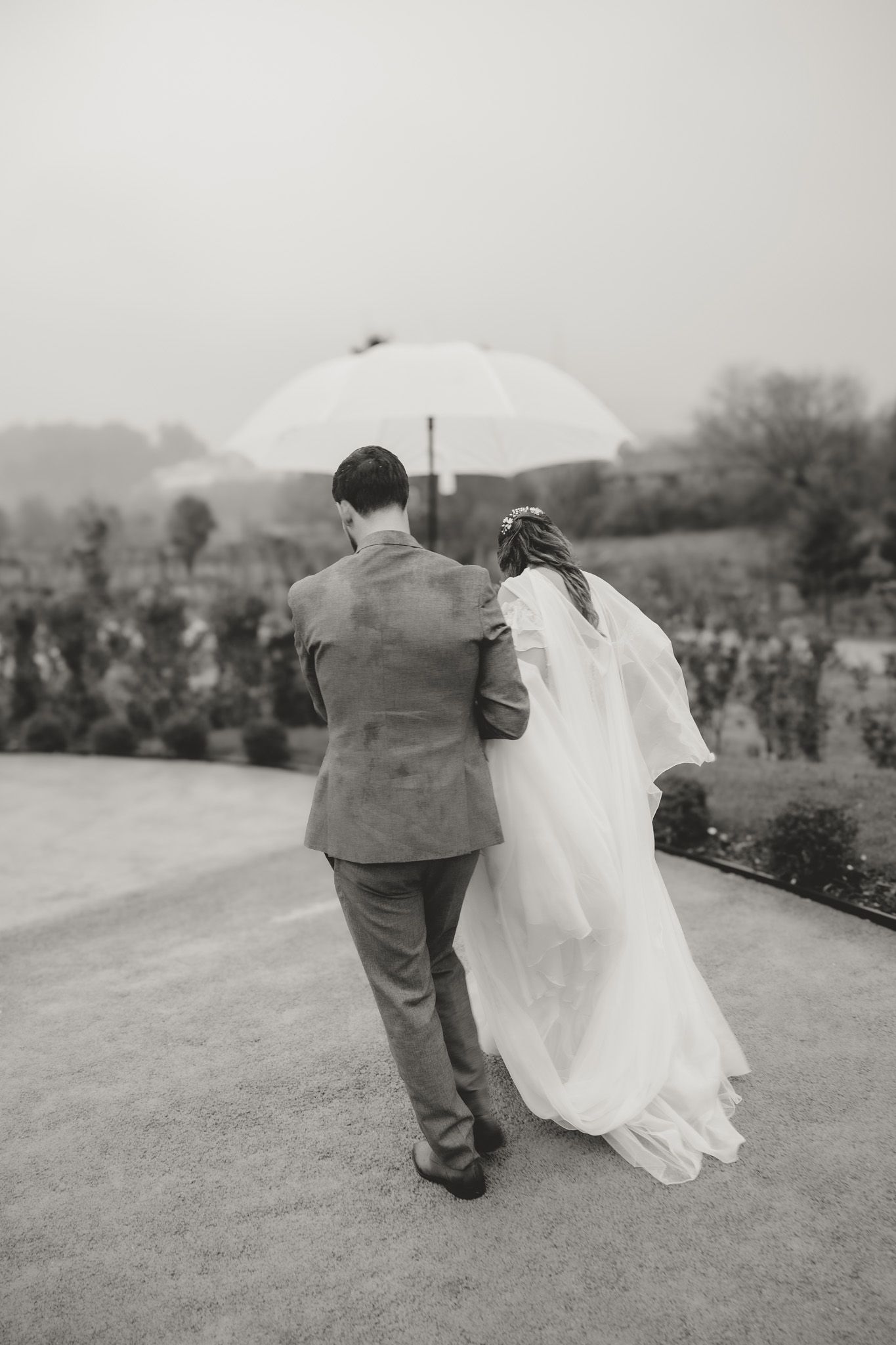 Black and white photo of couple walking together on grassy hillside path.