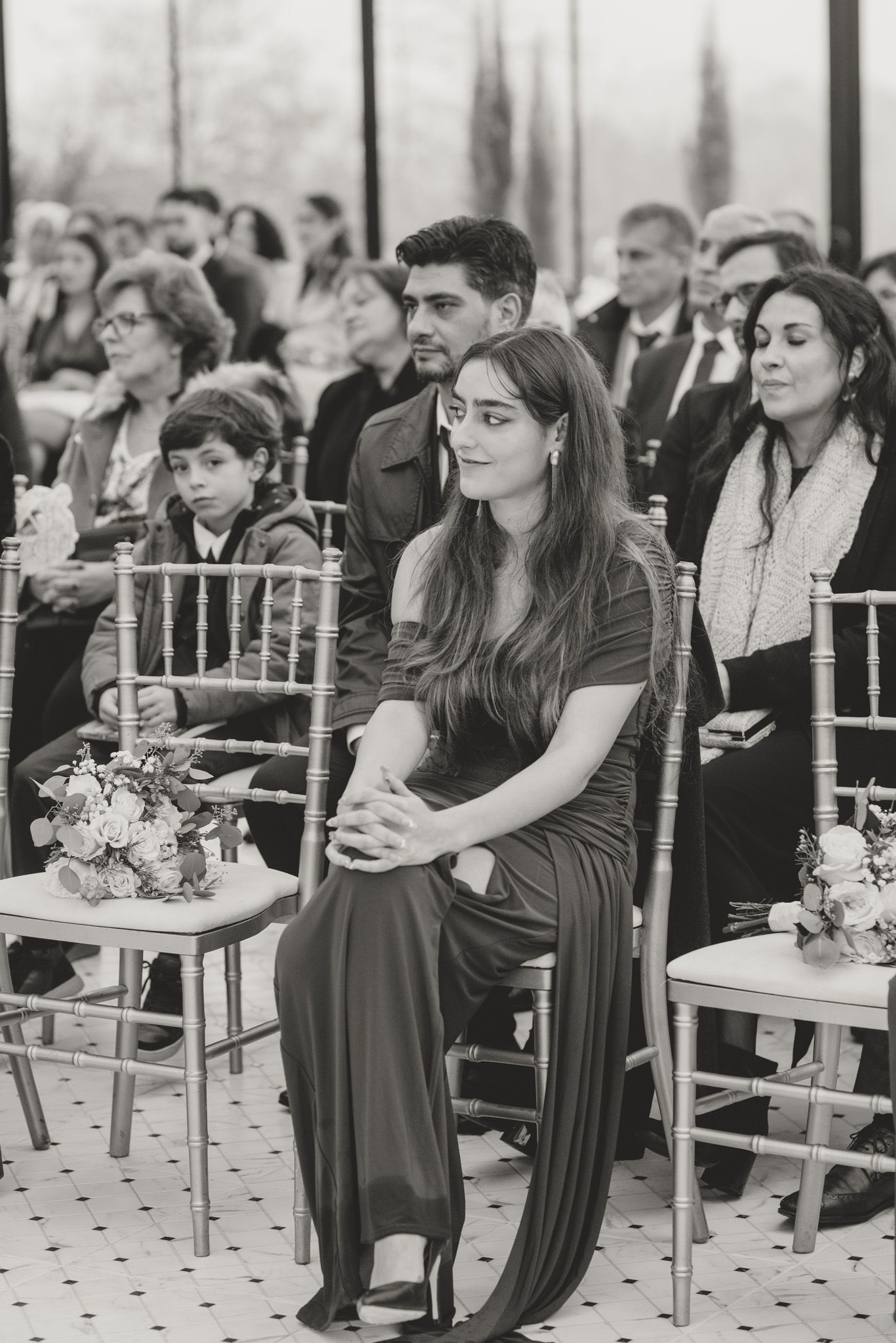 Wedding guests seated in elegant chairs during an indoor ceremony.