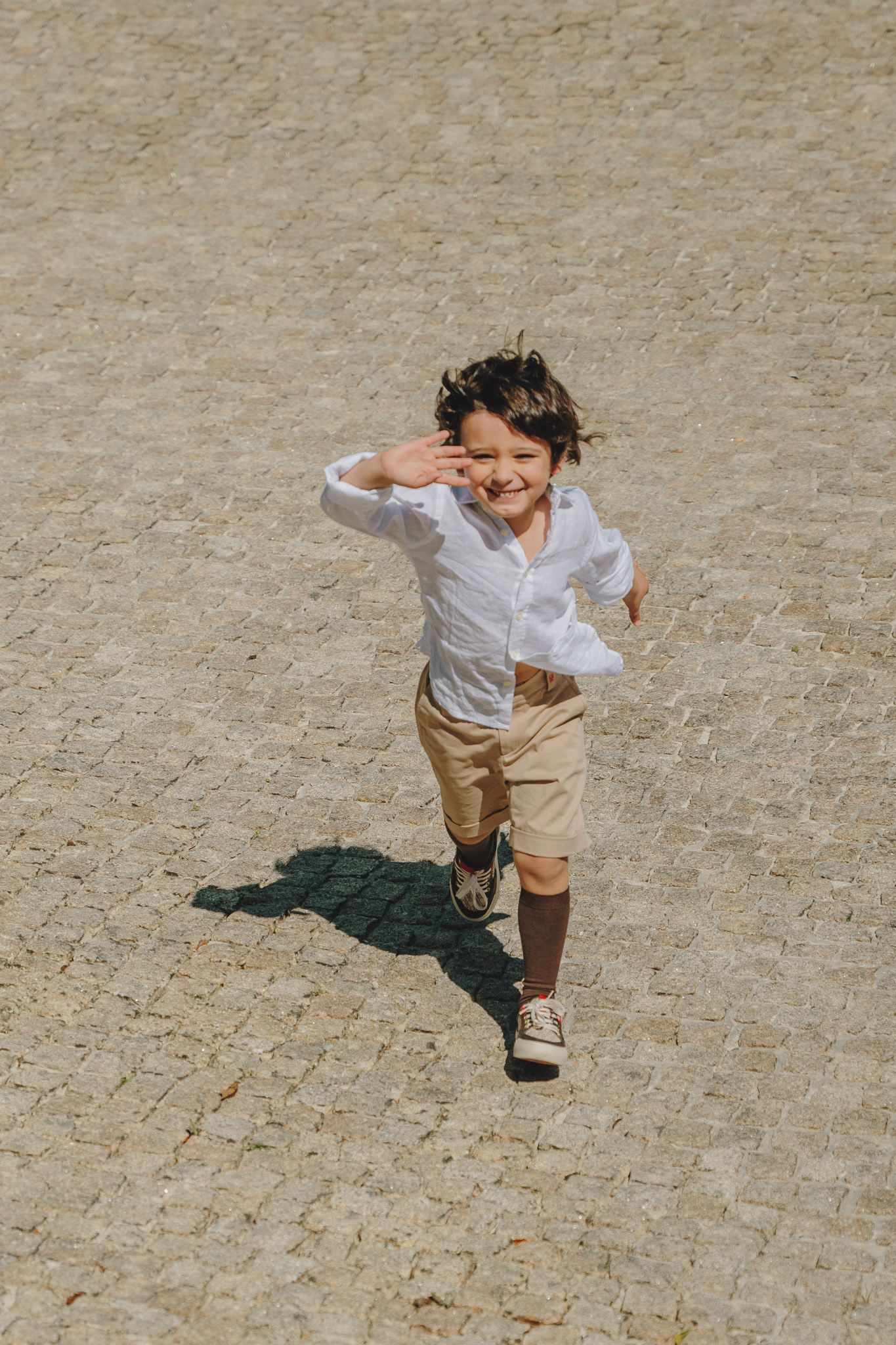 Dynamic shots of a child running and playing on a cobblestone surface.