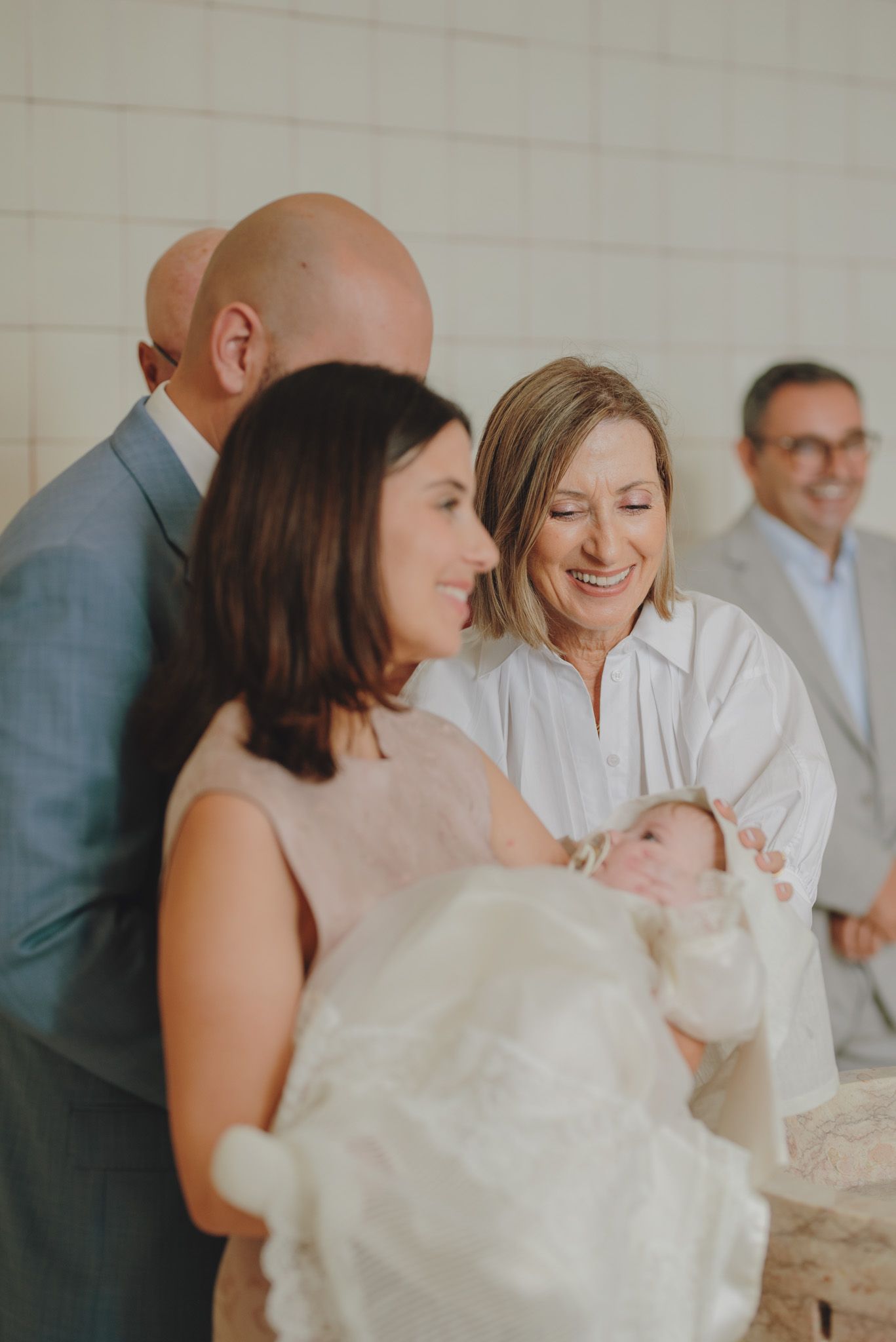 A tender moment during a baptism ceremony around a stone font in a modern church.