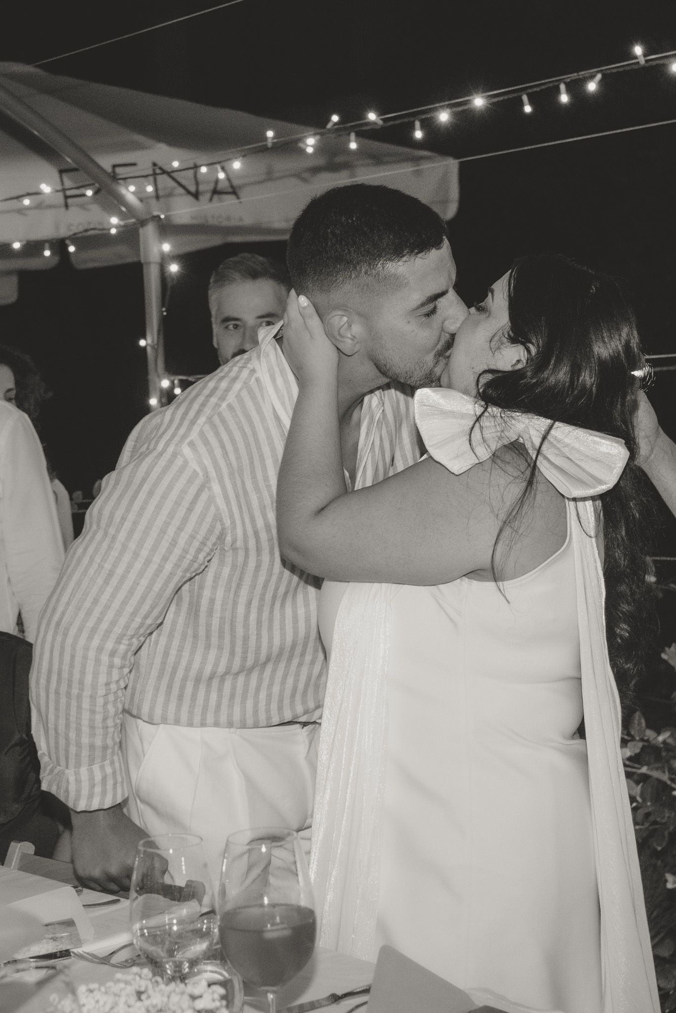 A romantic moment shared between a couple under string lights at an outdoor reception.