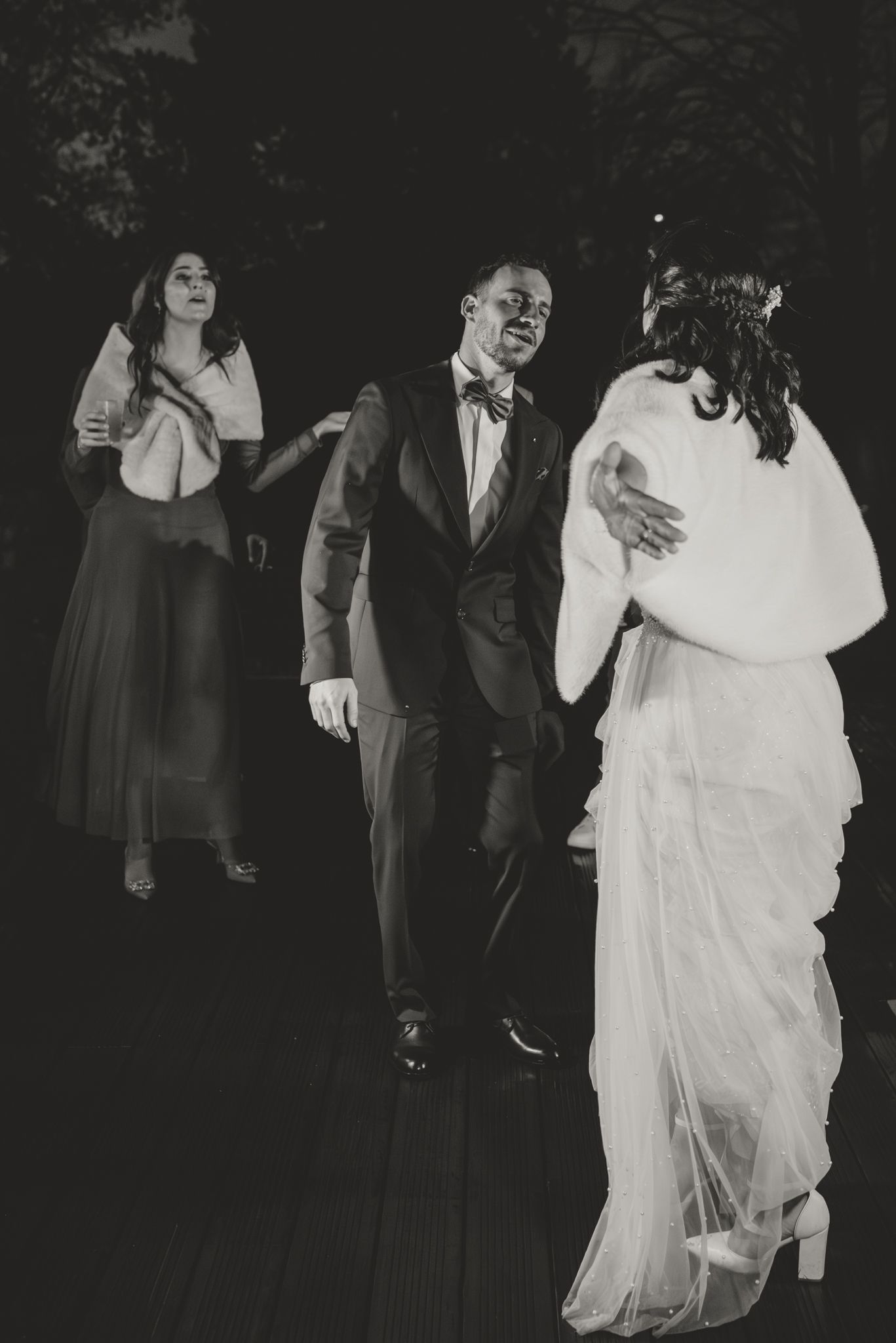 Wedding guests dancing and celebrating at an evening outdoor reception.
