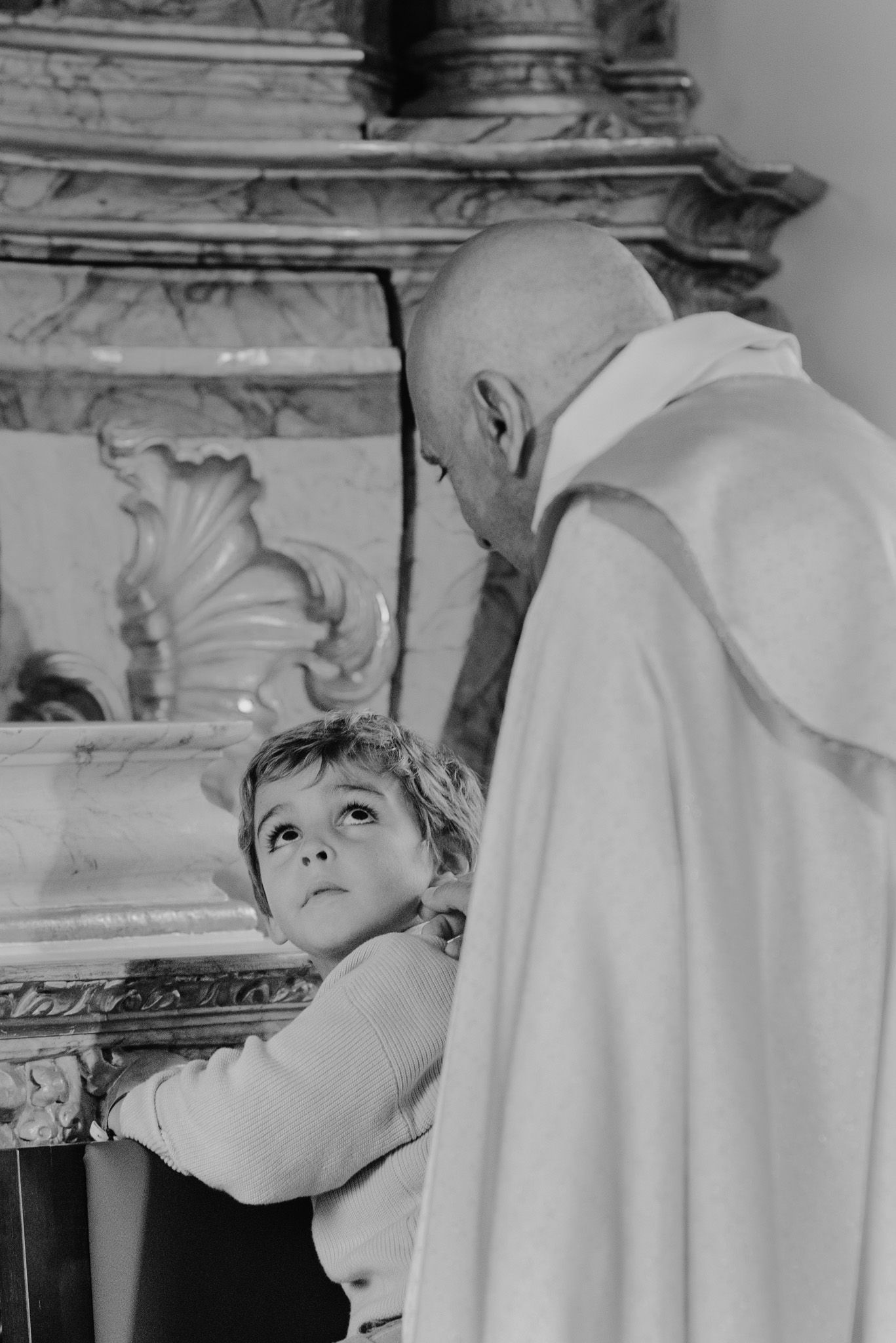 Black and white sequence showing a young child looking up at someone in white robes.