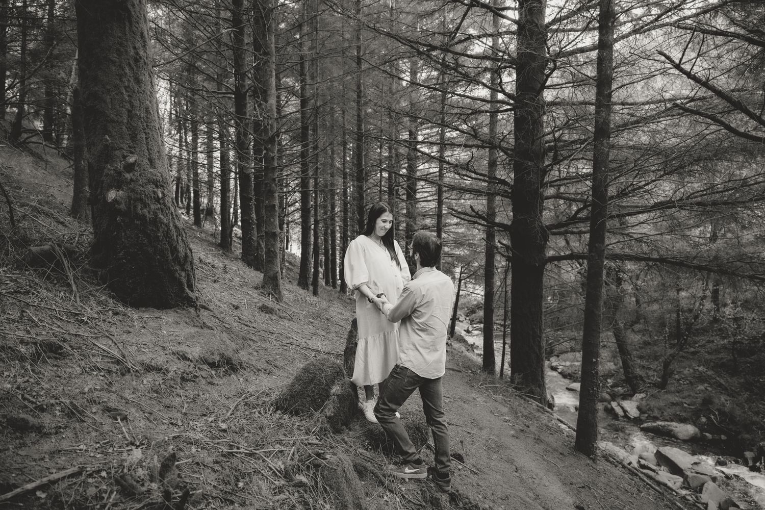 A black and white photo of two people walking along a misty forest trail.