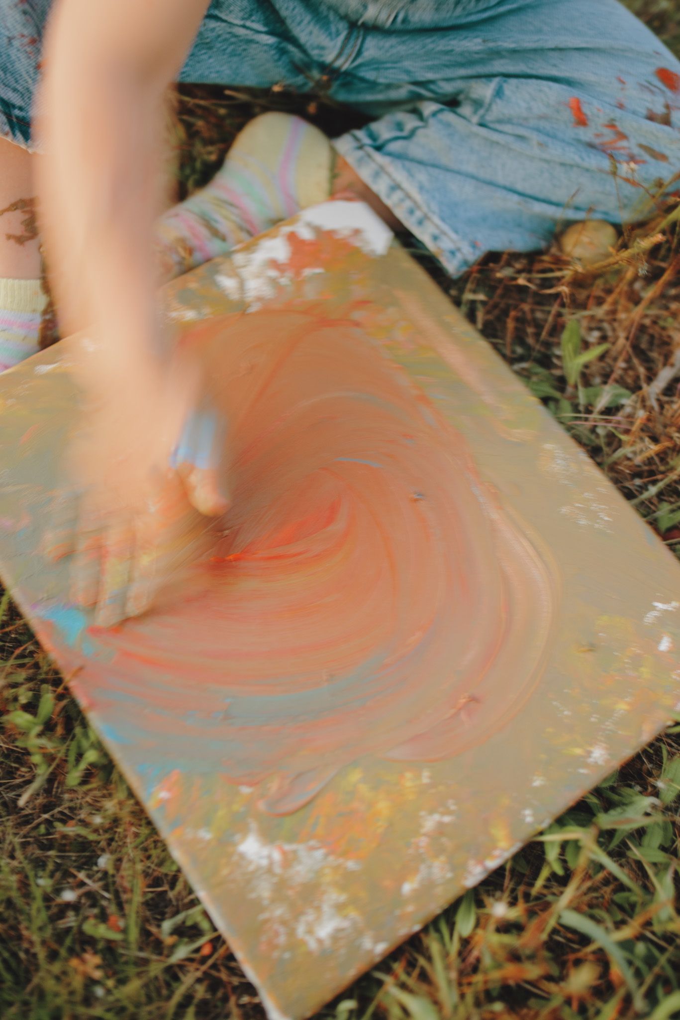 Creating swirling patterns in paint on an outdoor canvas.