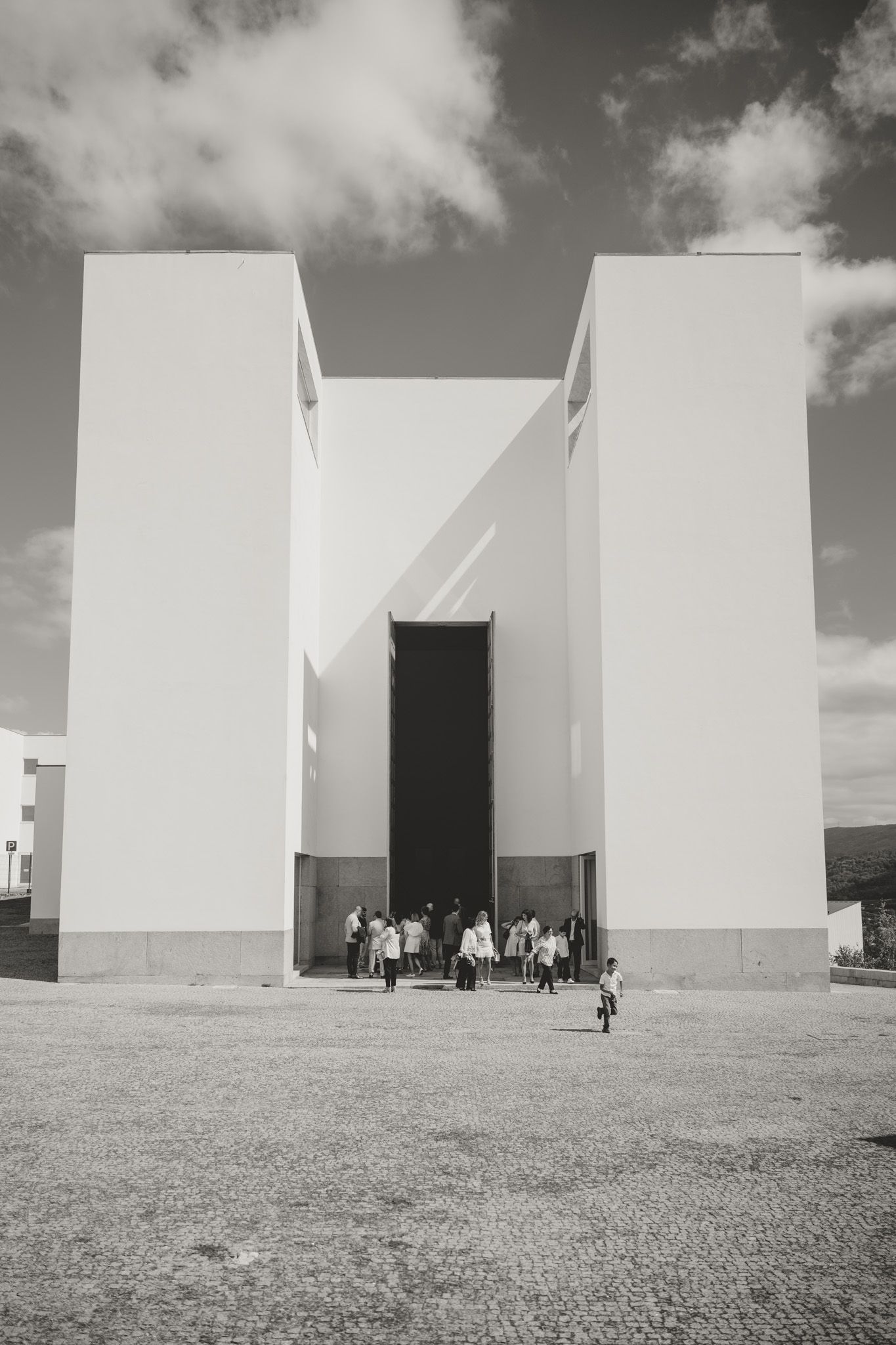 Modern white church buildings with geometric architecture against a cloudy sky.