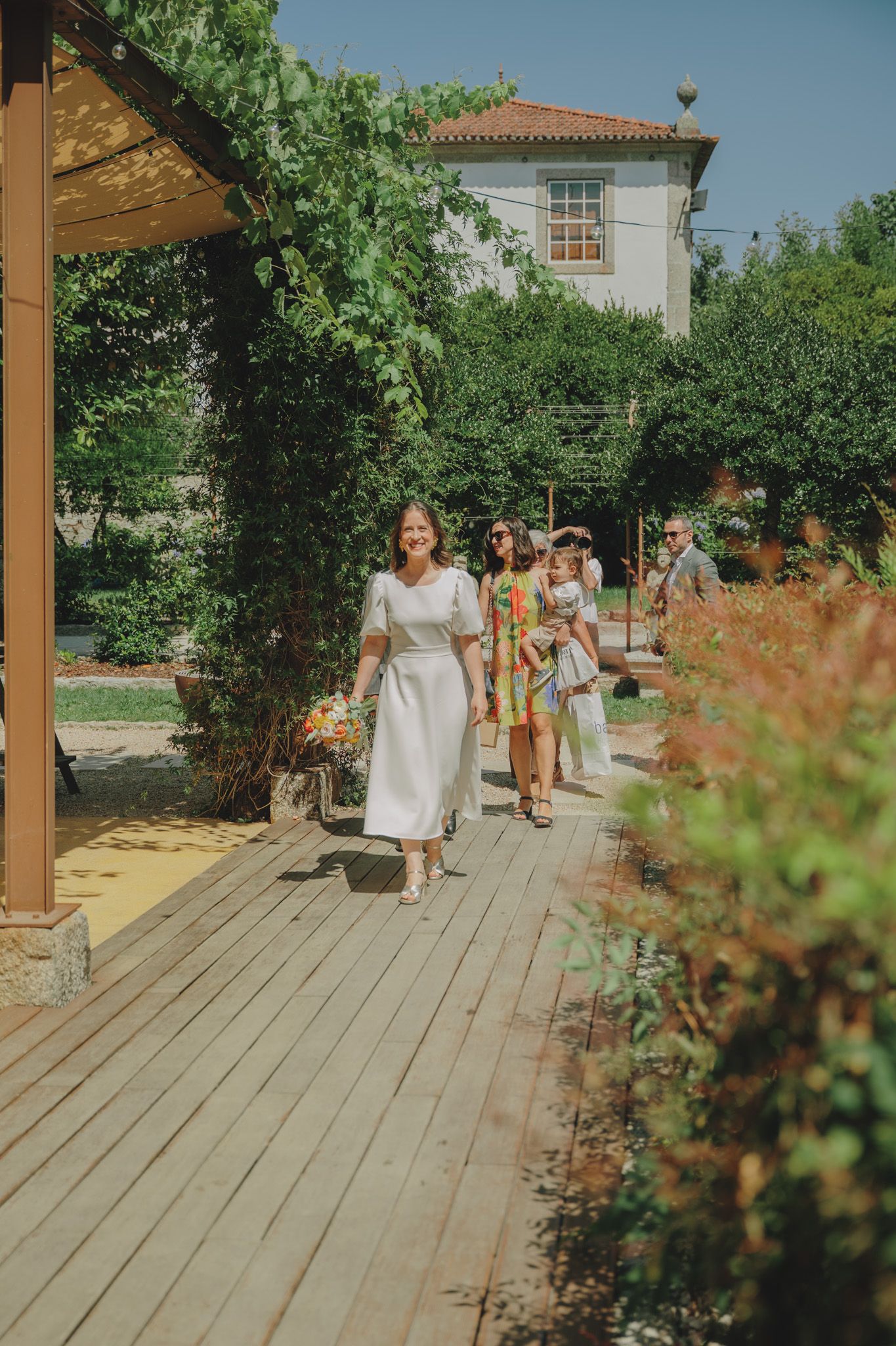 Wedding ceremony setup on a wooden deck with white chairs and natural greenery surroundings.