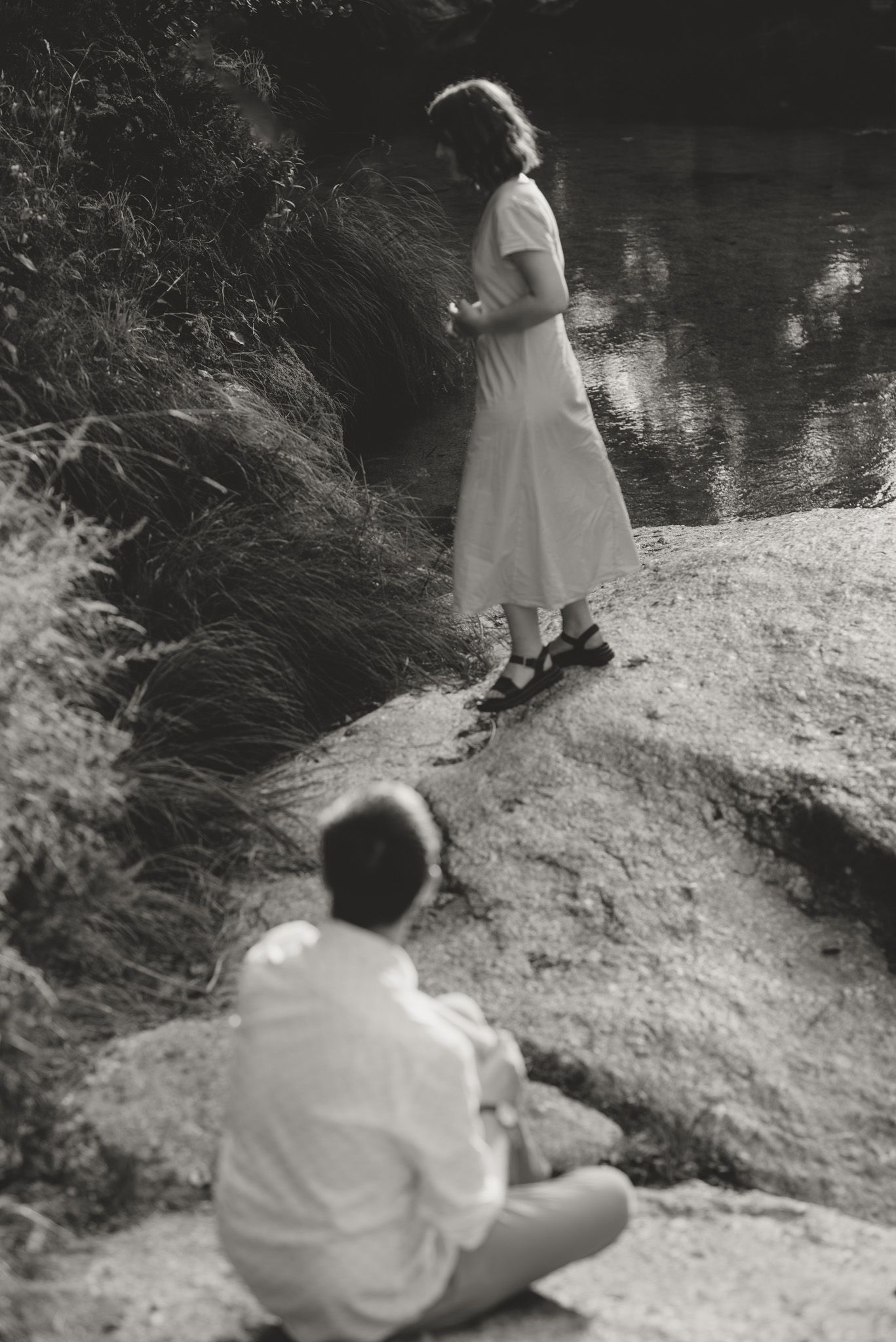 A sequence of black and white photos shows someone in white clothing sitting by a riverbank.