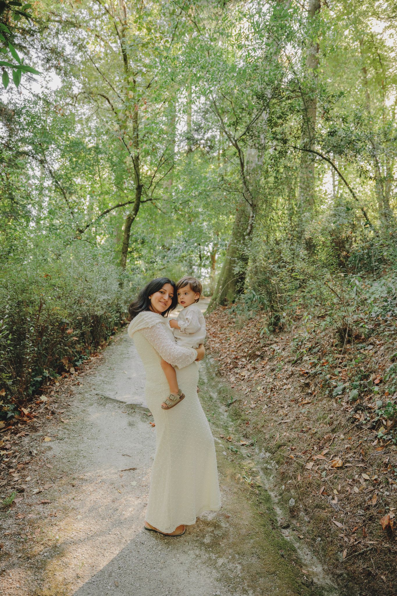 Couple in white dresses dances together on a wooded path.