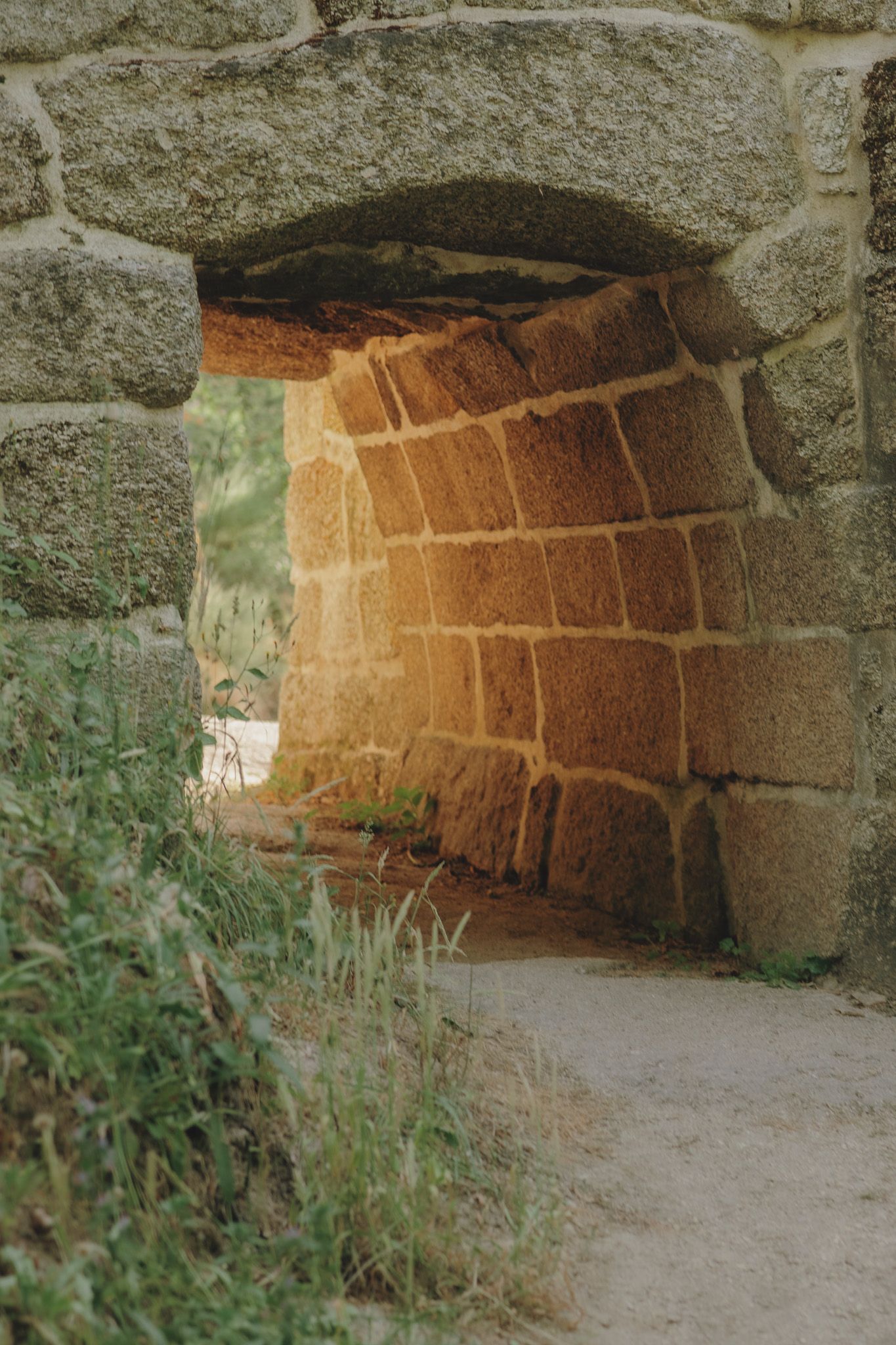 Ancient stone archway tunnel with rustic brick walls and natural light filtering through.
