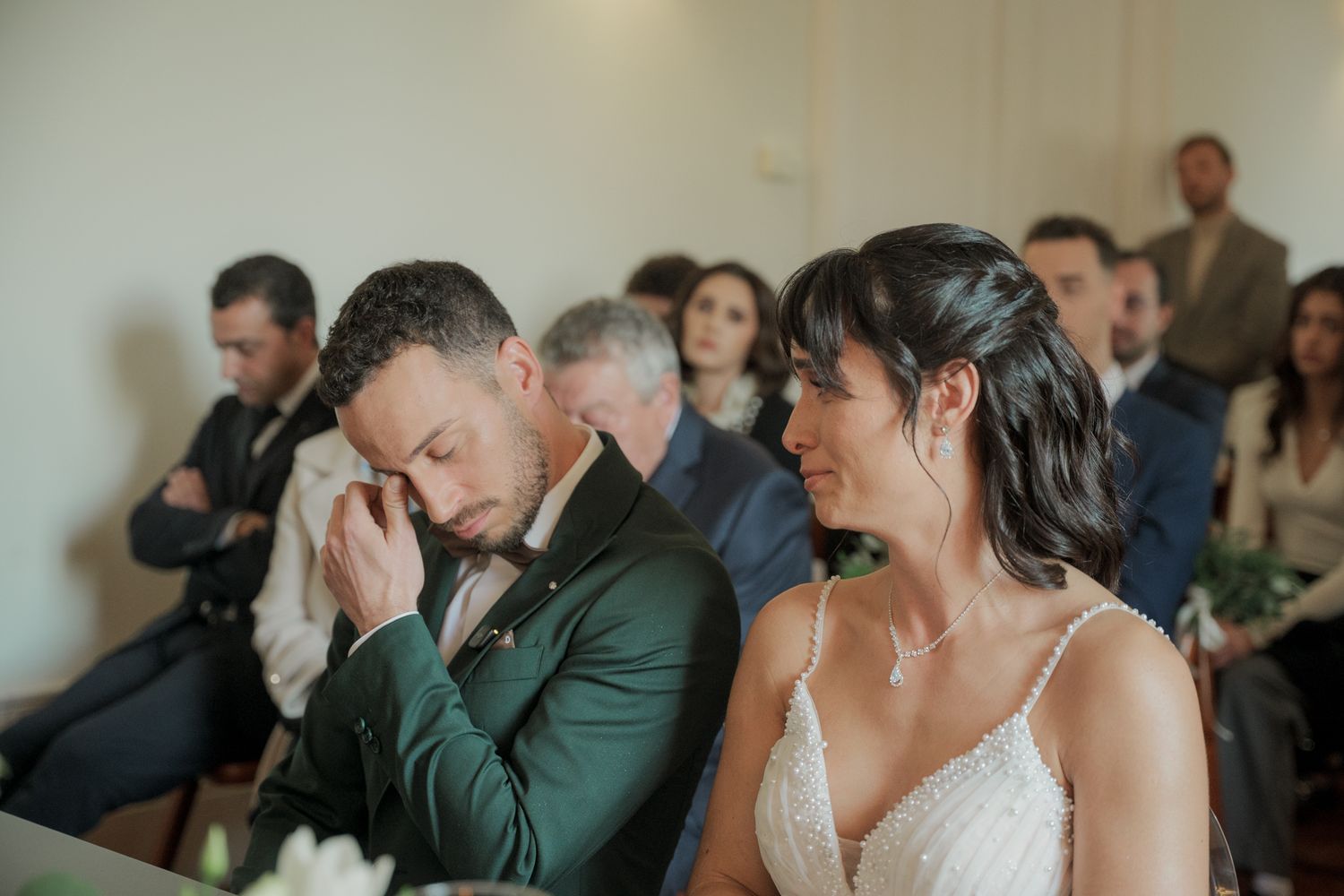 Wedding guests seated in rows during an emotional ceremony moment.