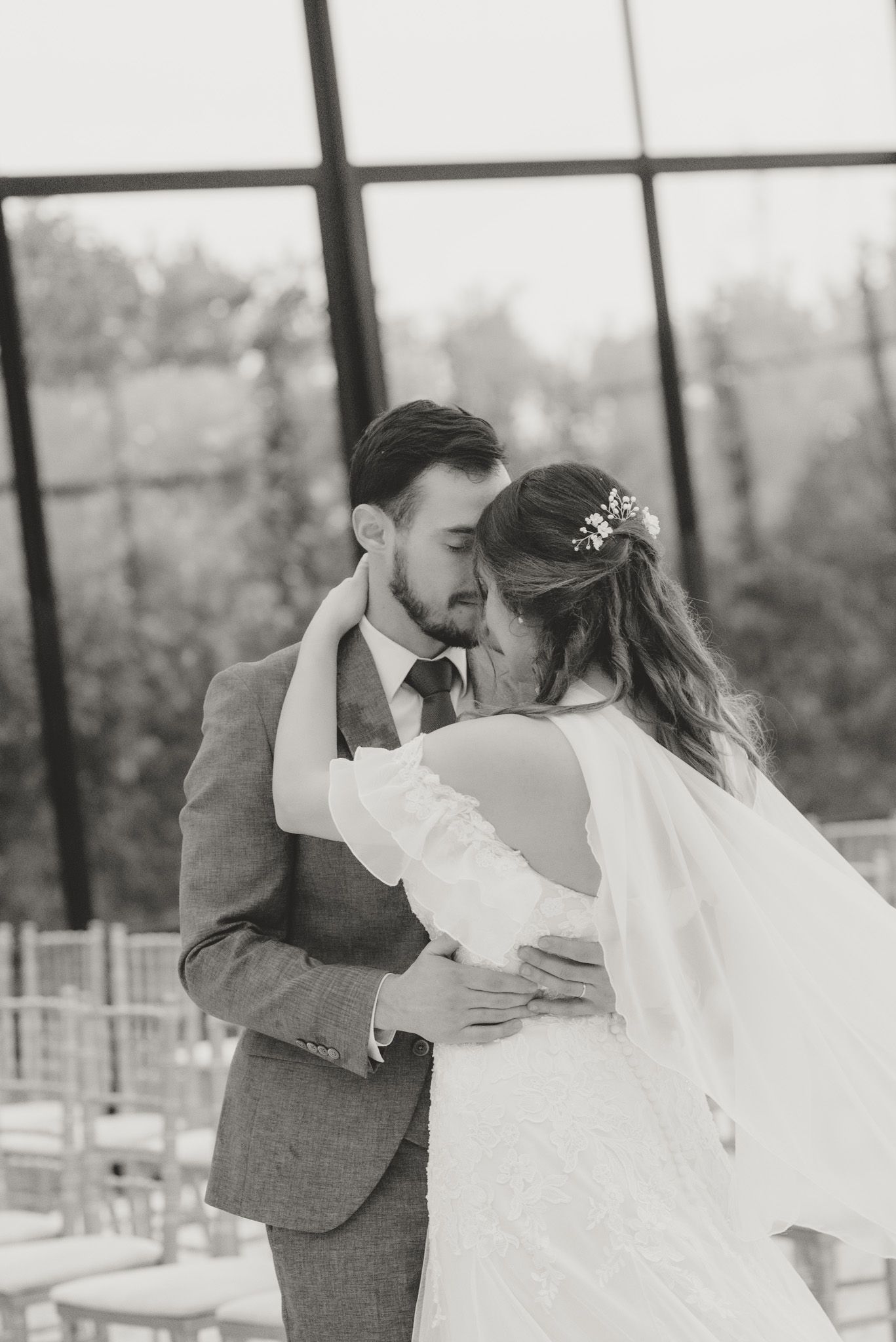 Black and white portrait of couple dancing together in elegant wedding attire.