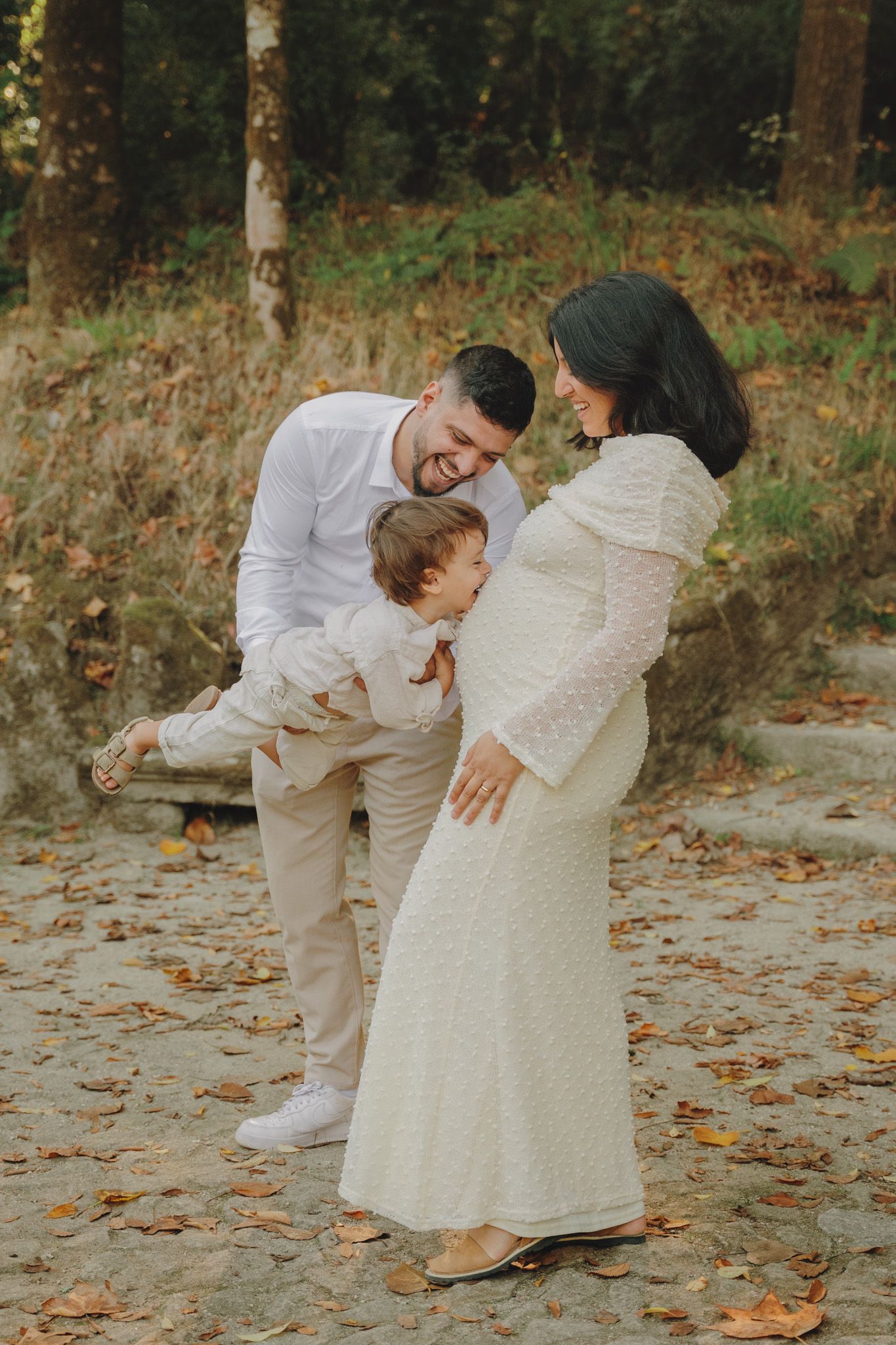 A playful family moment captured outdoors with fallen leaves and natural scenery.