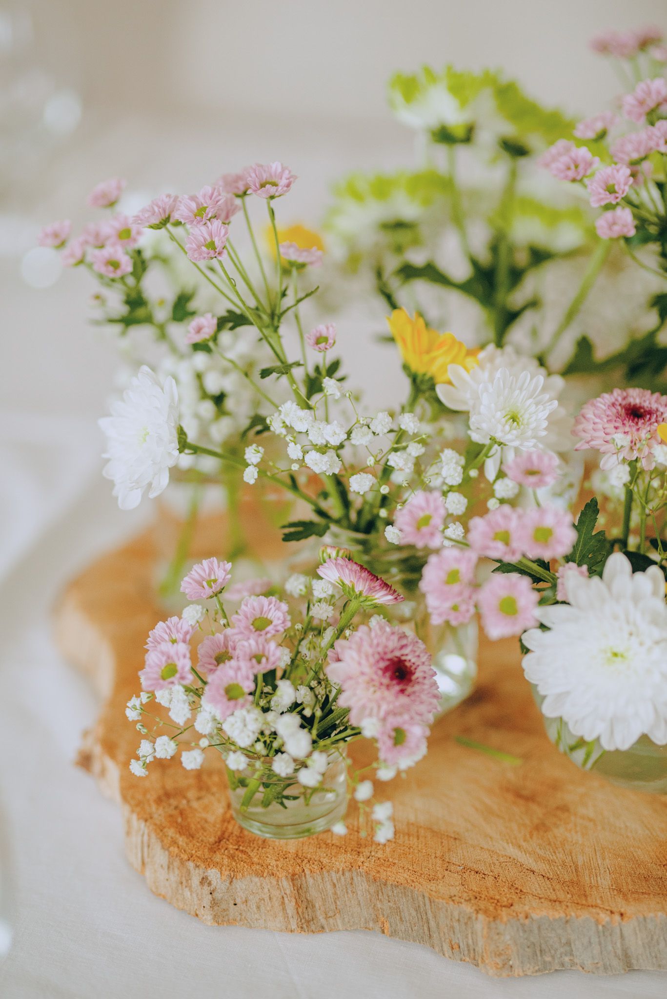 Delicate pink and white flowers arranged on rustic wooden surface.