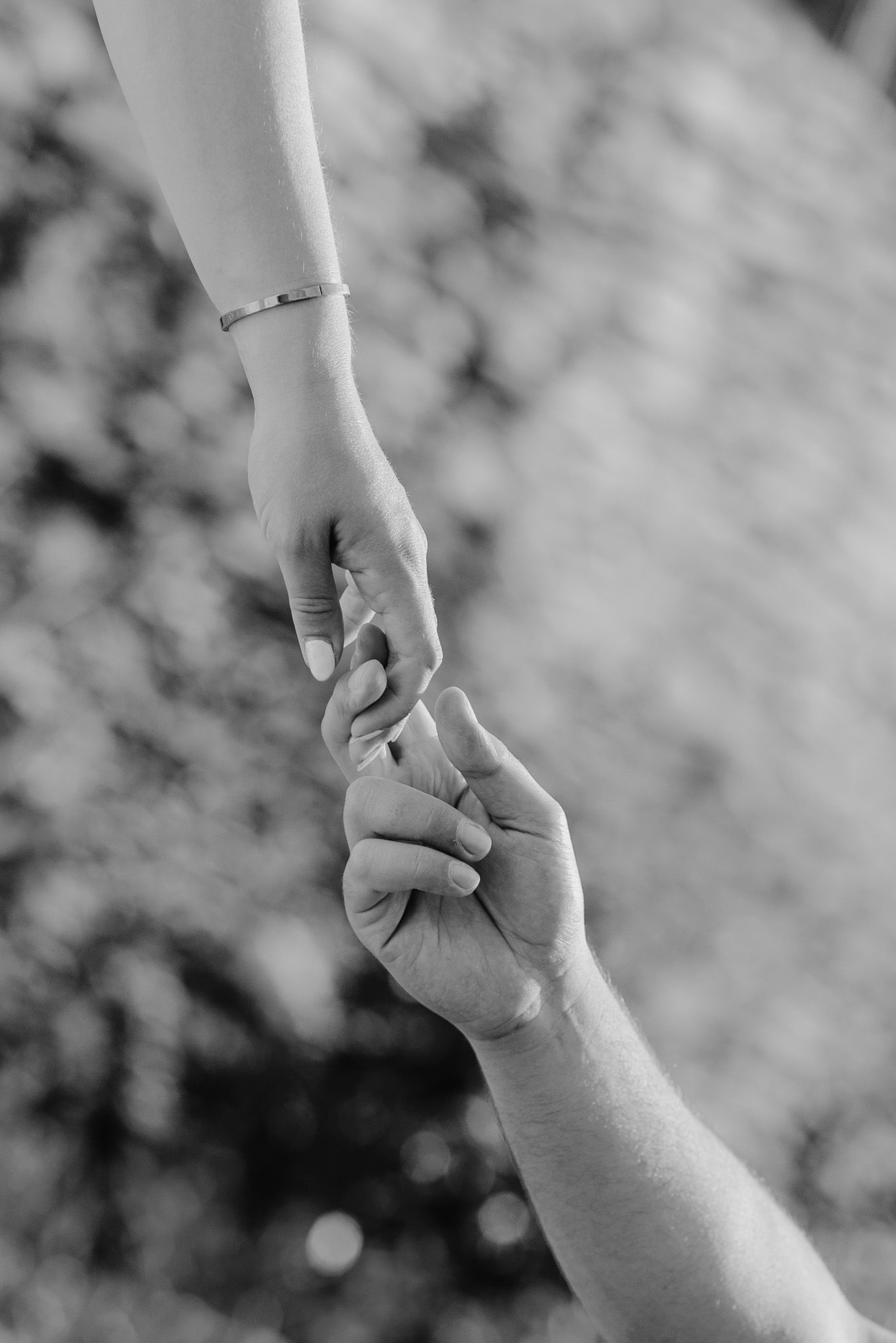 Close-up black and white image of two hands tenderly clasping together.