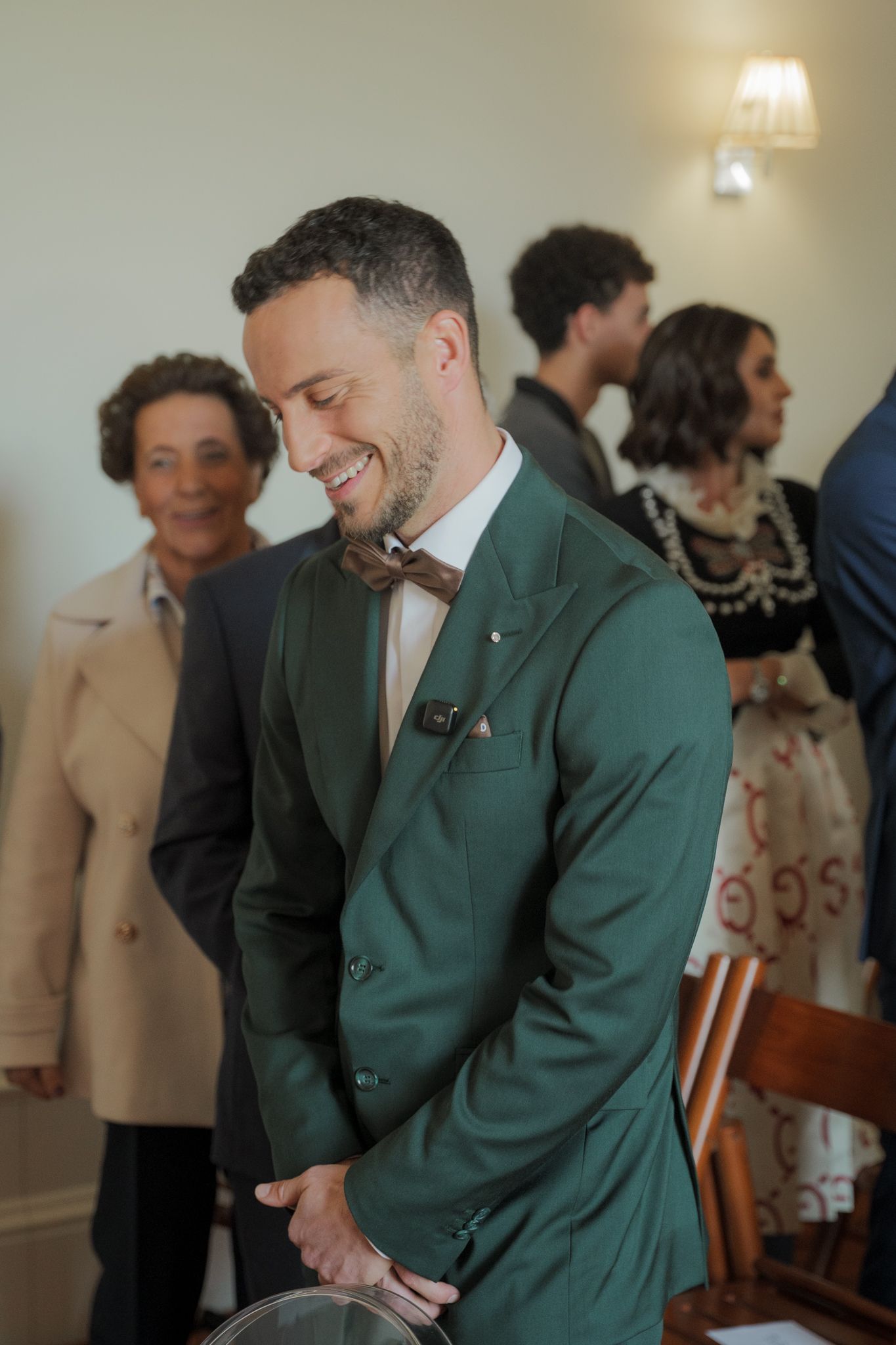A person in a green jacket shares a lighthearted moment during an indoor celebration.