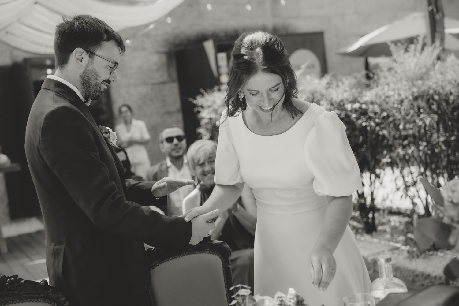 Guests celebrate at an outdoor wedding reception under string lights and fabric draping.