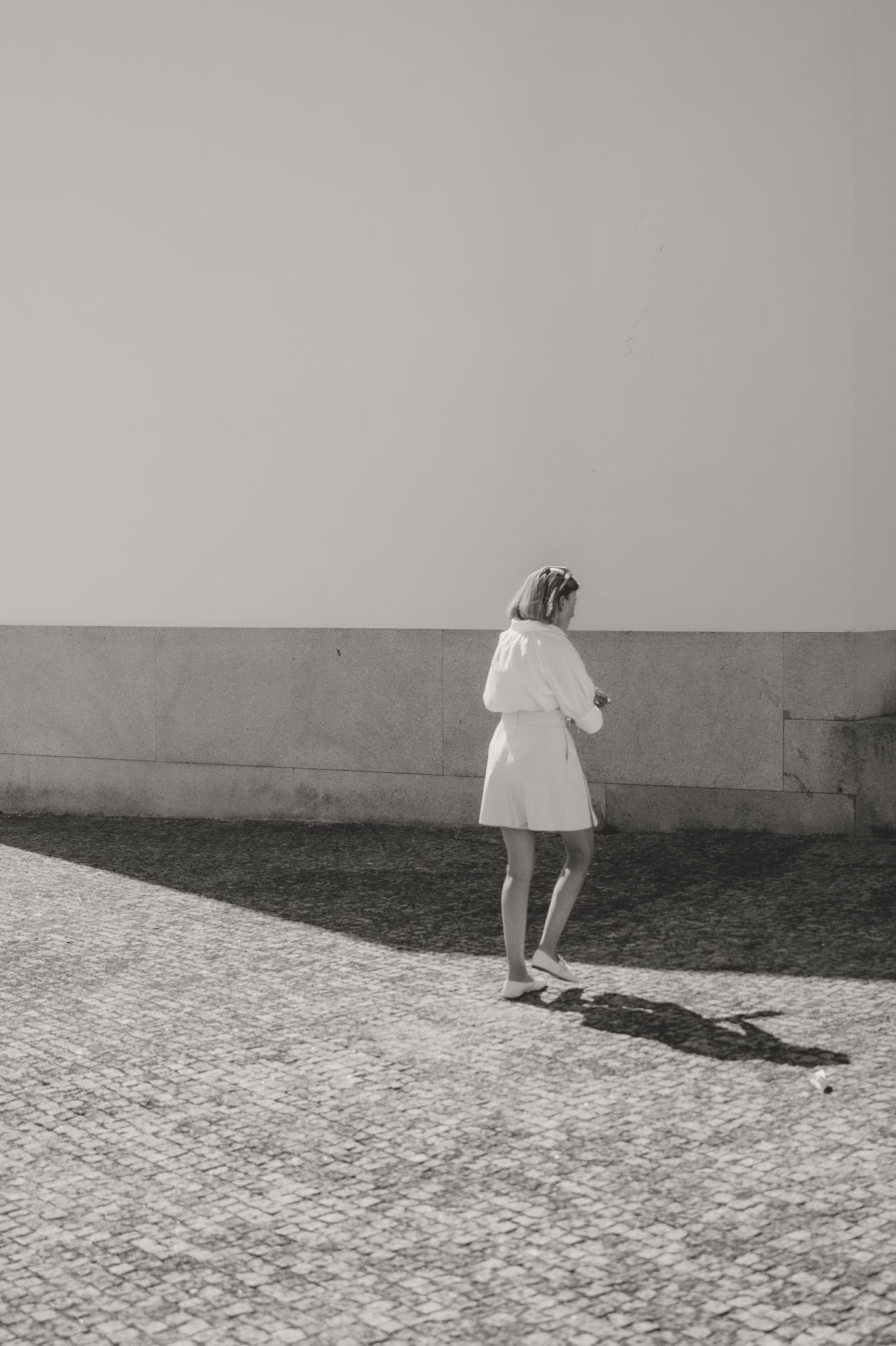 A sequence of black and white photos showing a figure walking across a stone-paved surface.