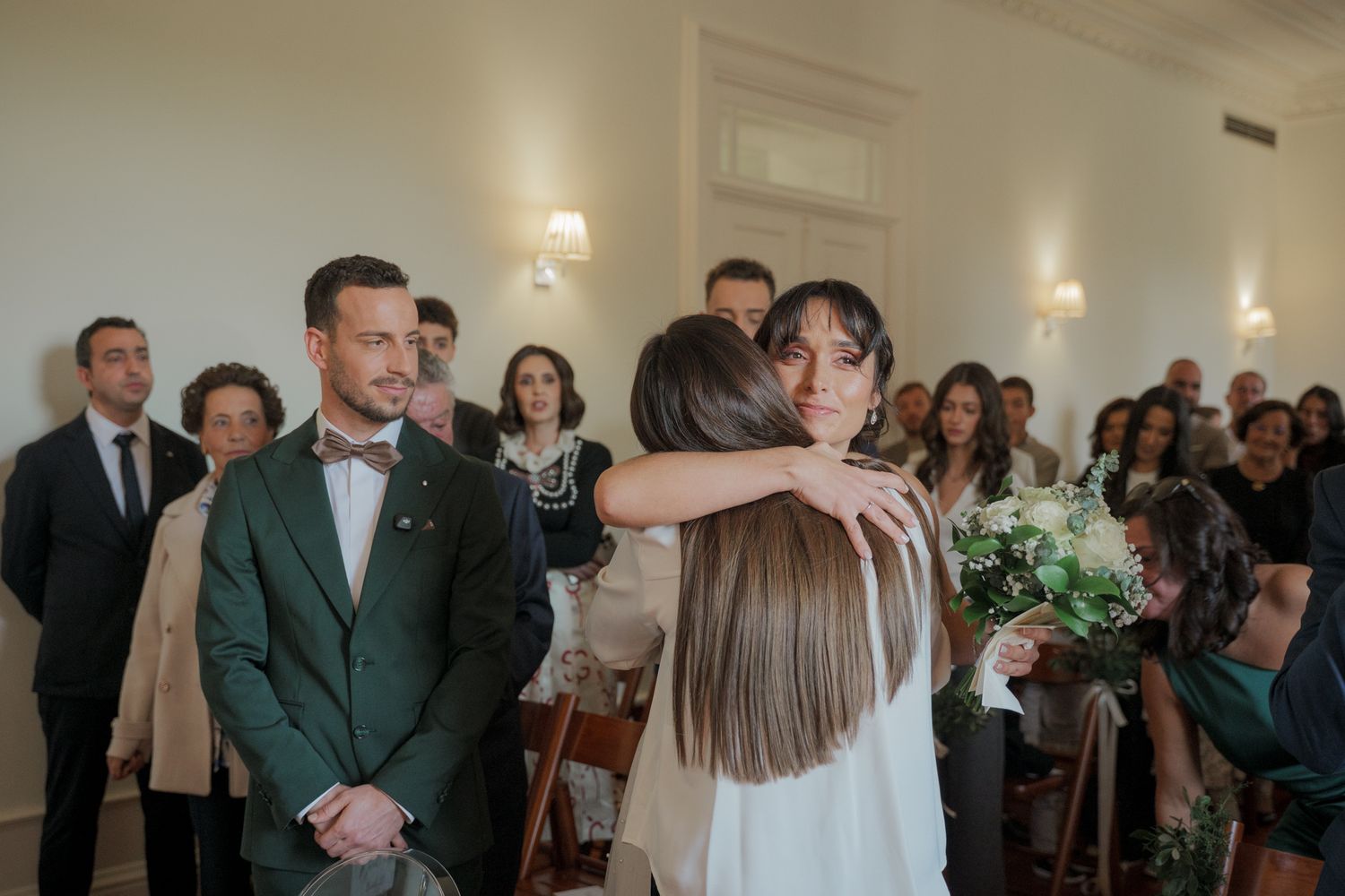 Wedding celebration in a bright indoor venue with guests mingling and ornate architectural details.