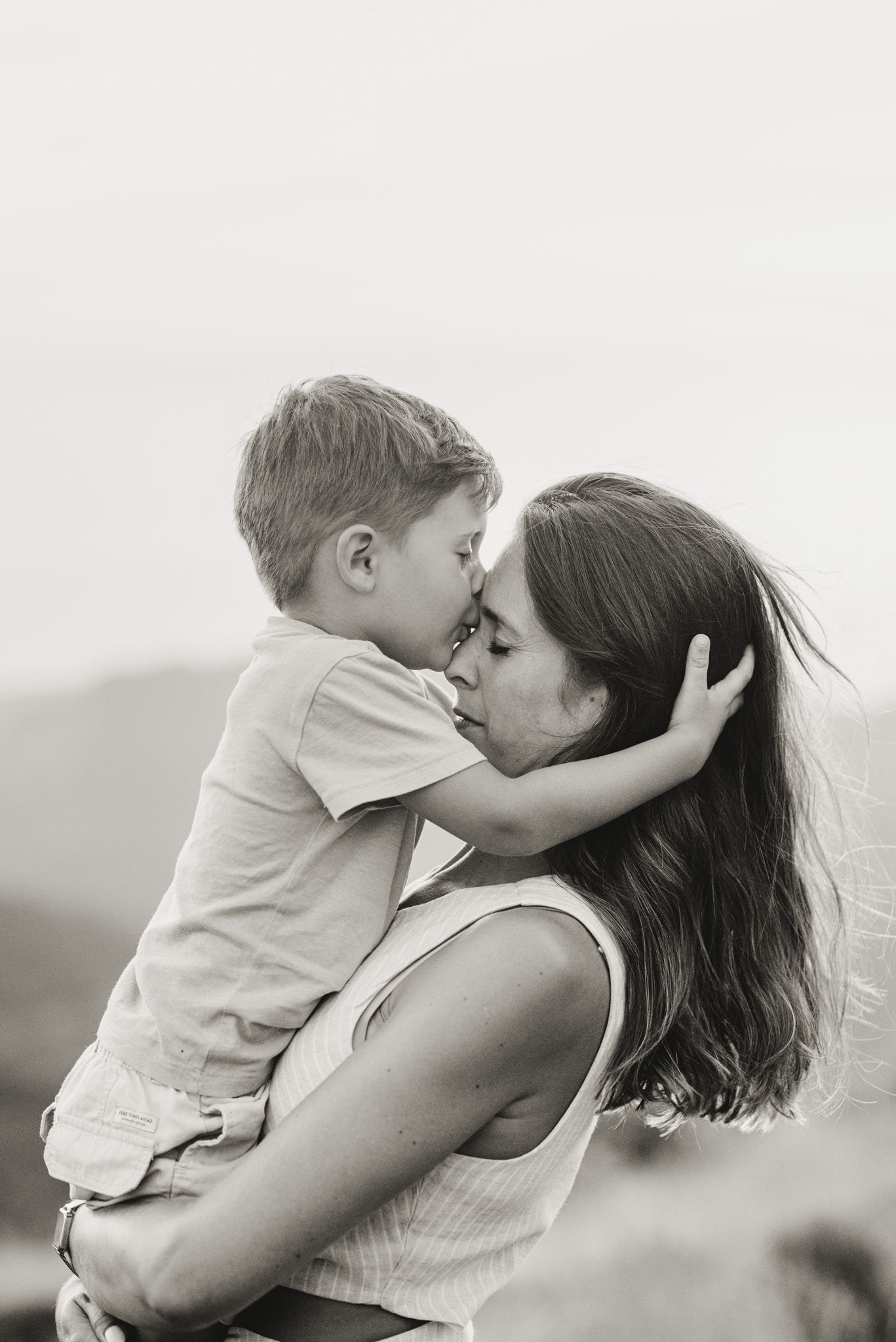 A tender black and white sequence of three photos showing a parent and child sharing an affectionate moment together.