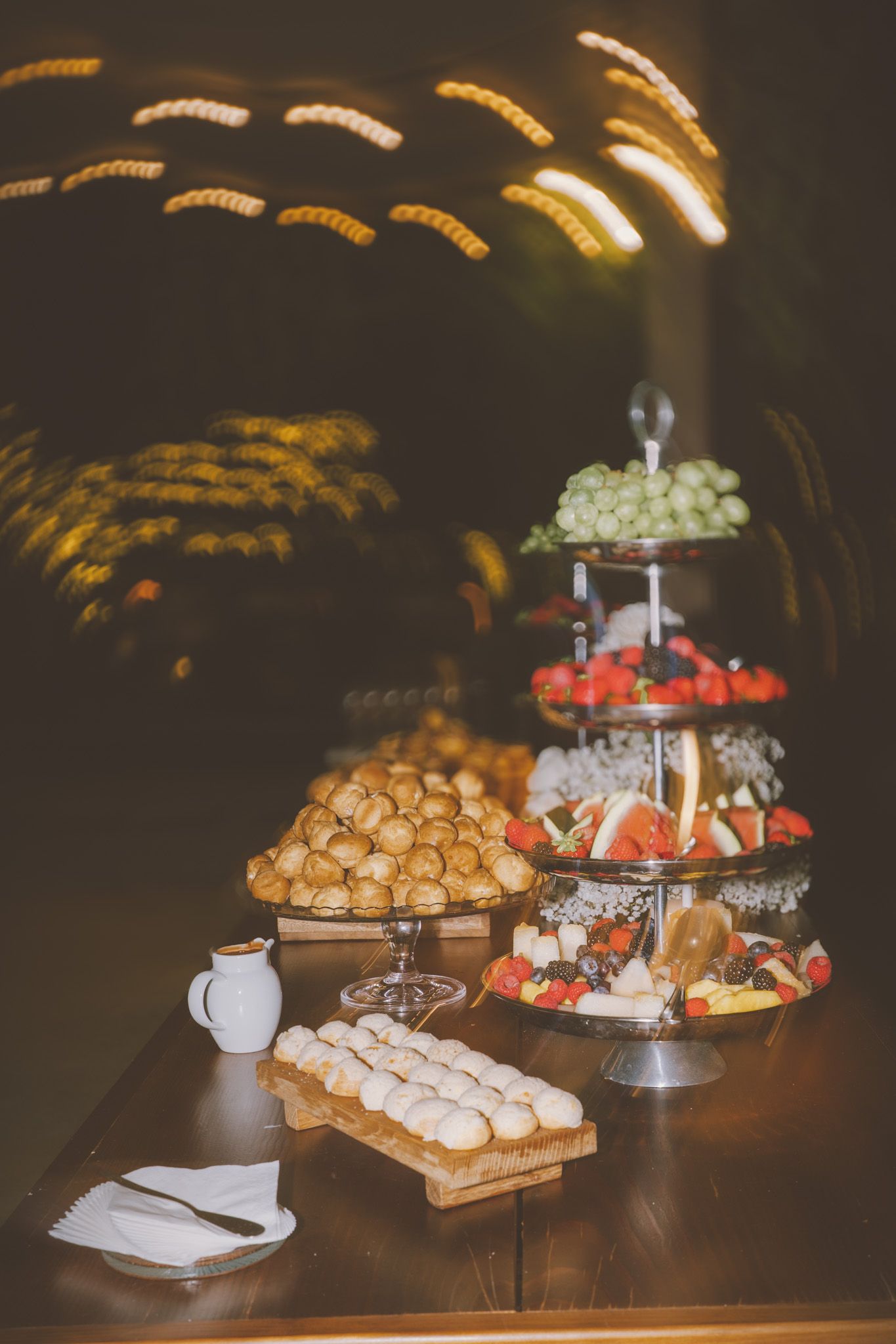 Multi-tiered dessert display featuring pastries and treats on an elegant wooden table.