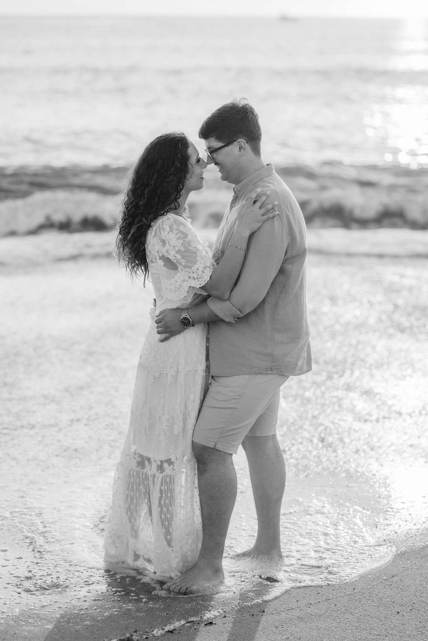 A couple shares an intimate embrace while standing in shallow ocean water.