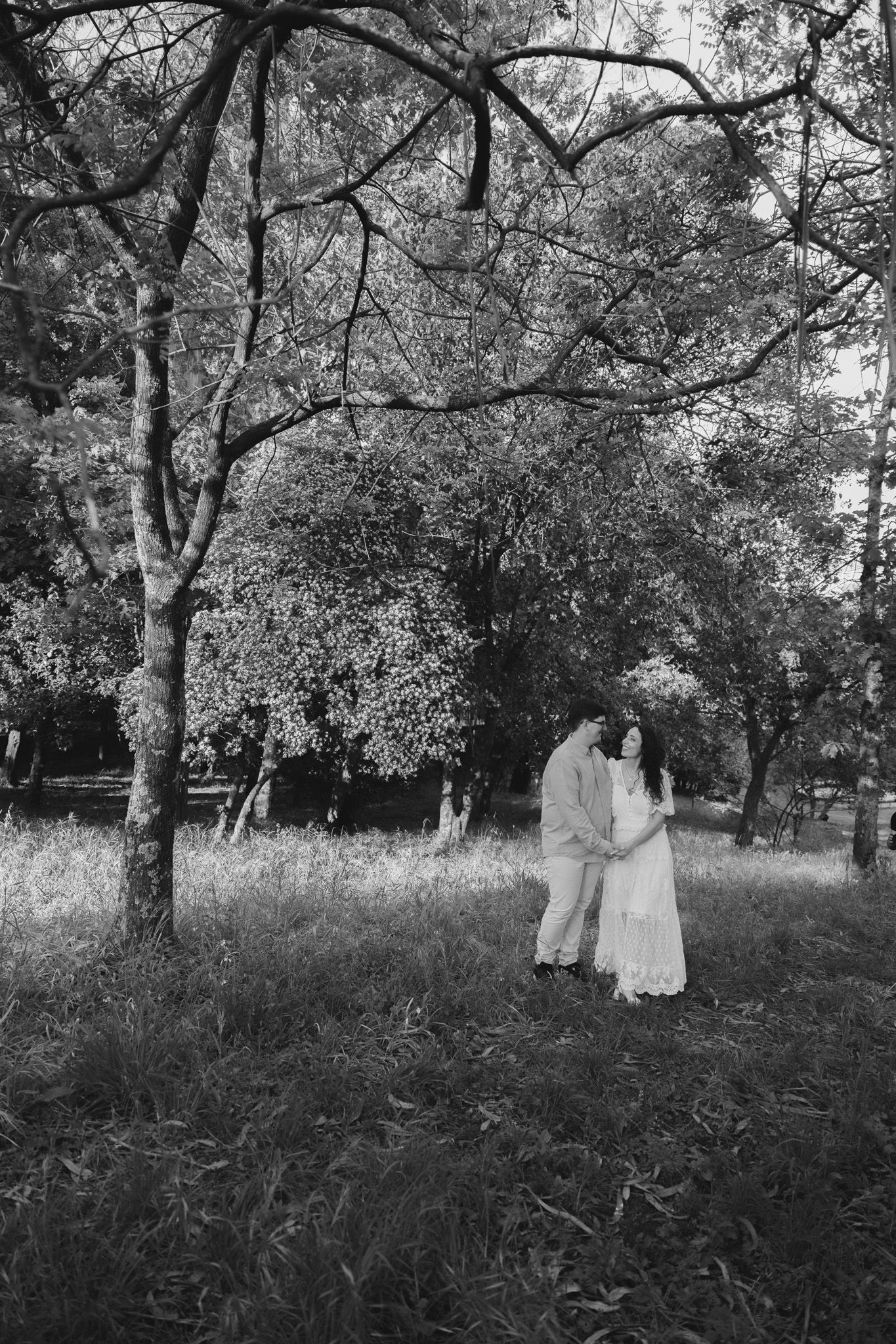 Black and white photo of a couple walking through a serene garden landscape.