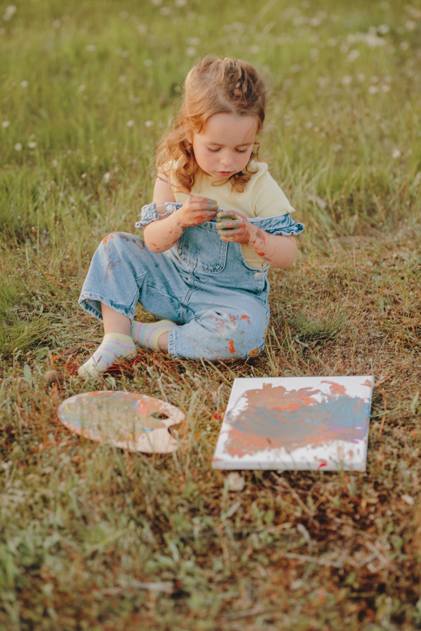 Young reader explores a book while sitting in a sunlit meadow with wildflowers.