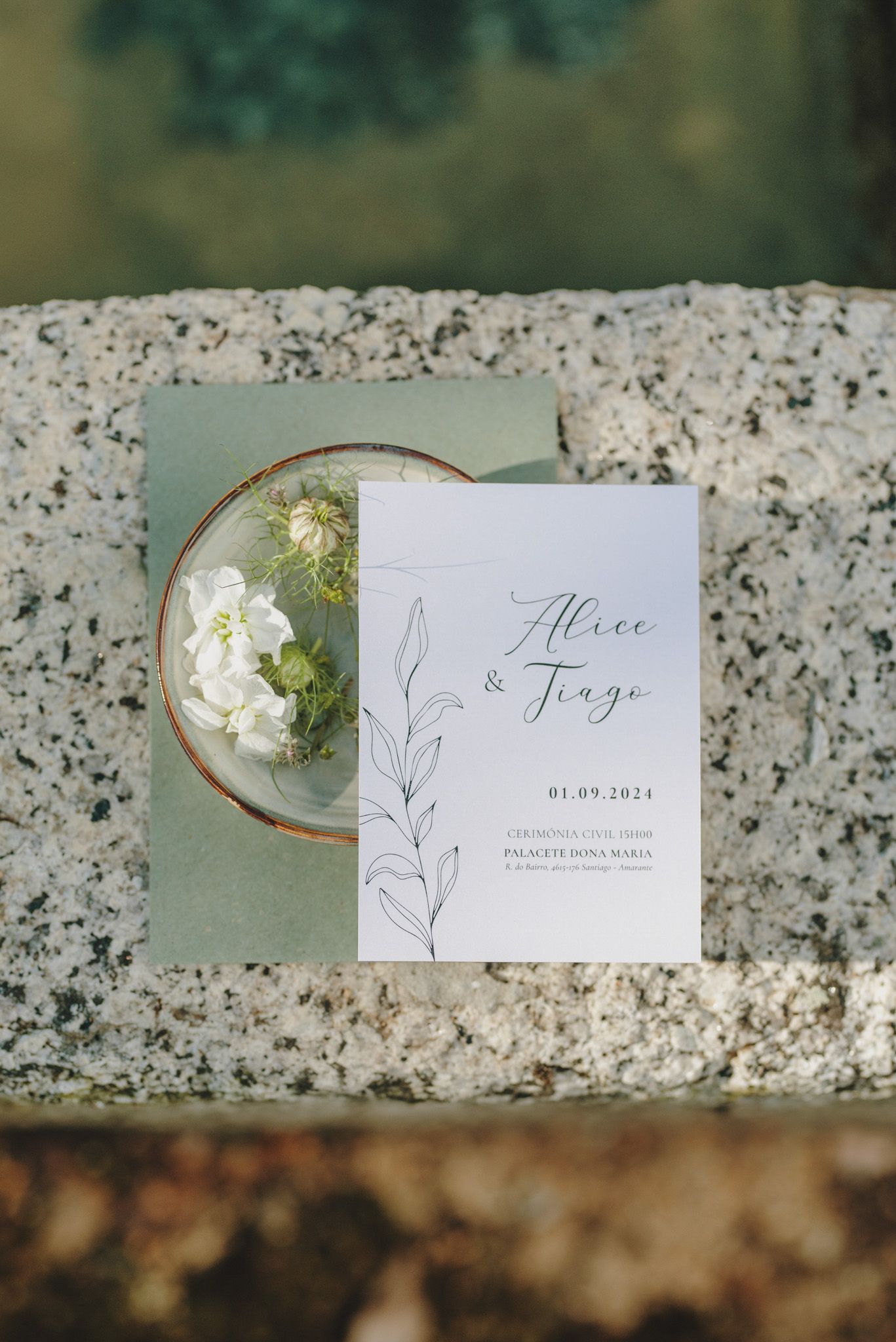 Elegant wedding invitation suite with white floral details and calligraphy text displayed on a marble surface with gold accents.