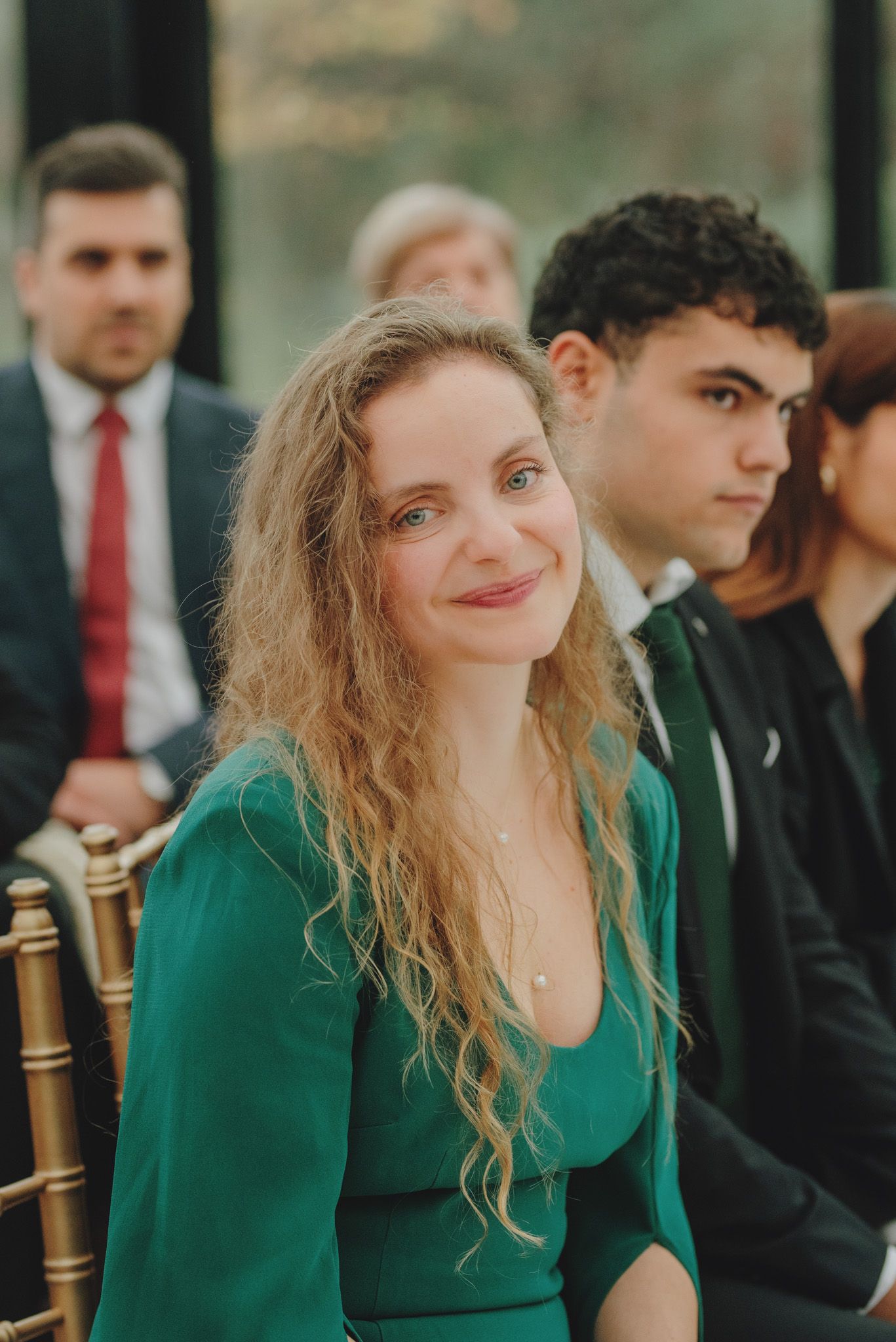 Wedding guest in emerald green dress reacts emotionally during ceremony.