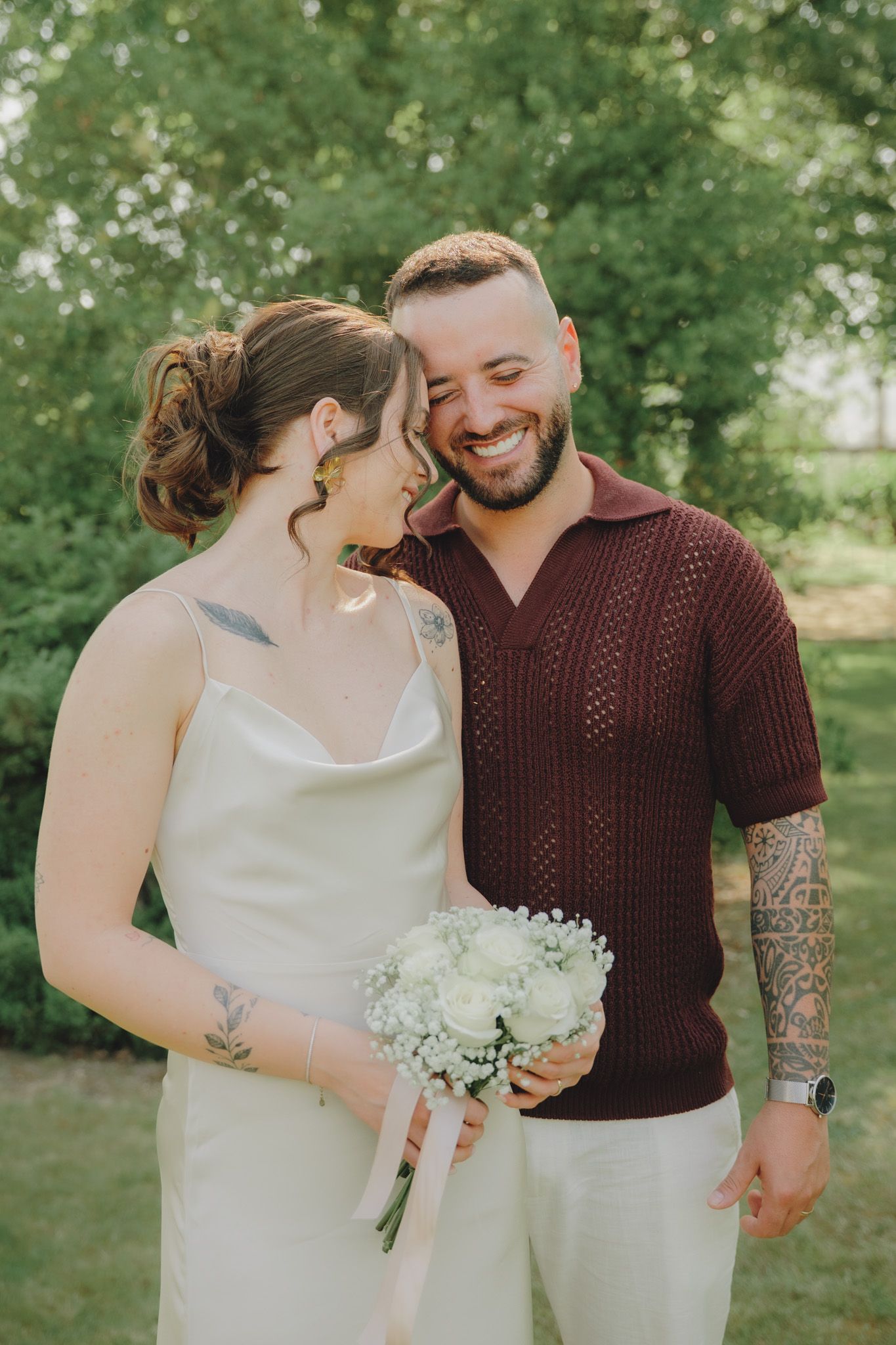 A couple shares a joyful moment in a garden setting with white flowers.
