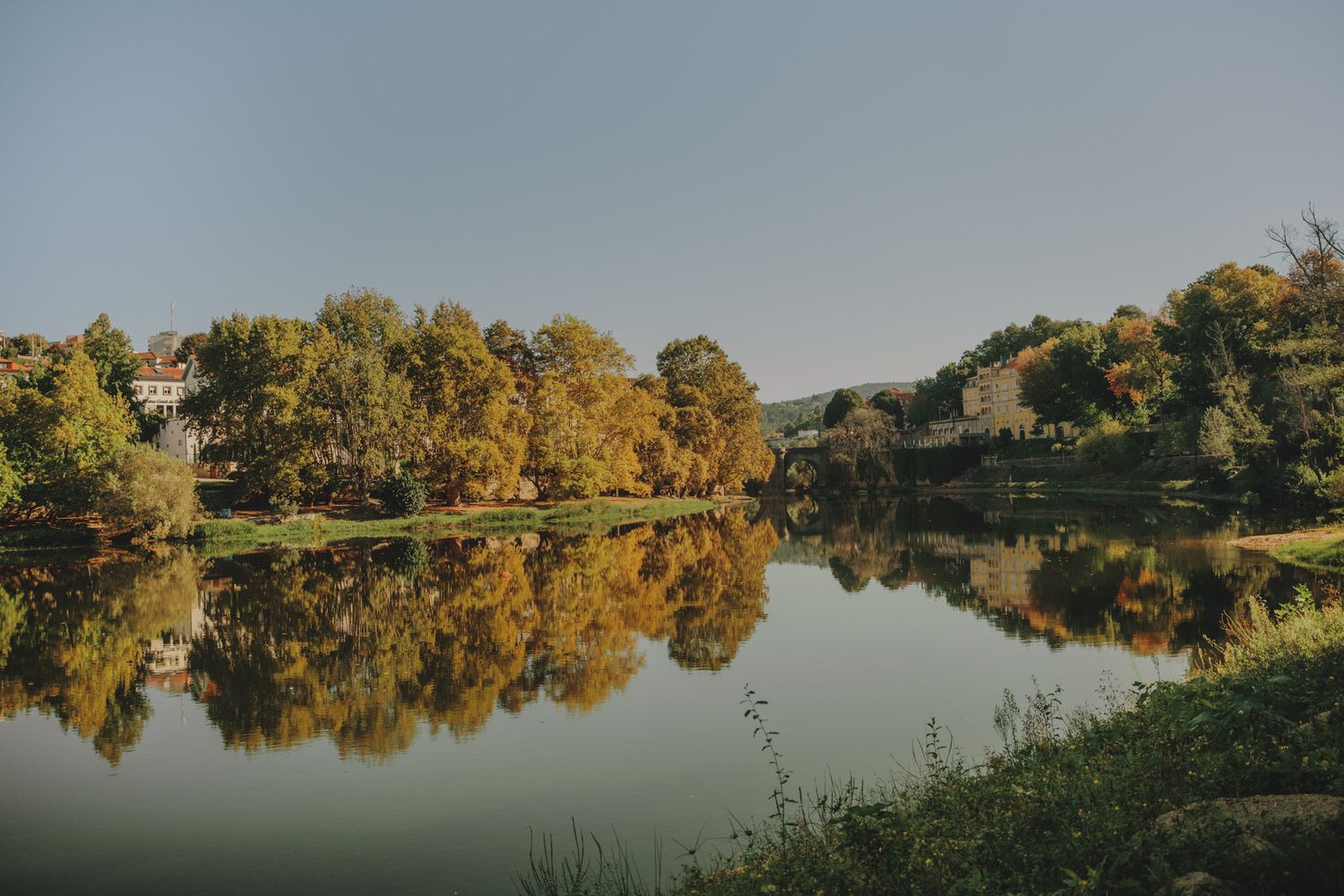 Panoramic view of lake reflecting autumn trees along shoreline.