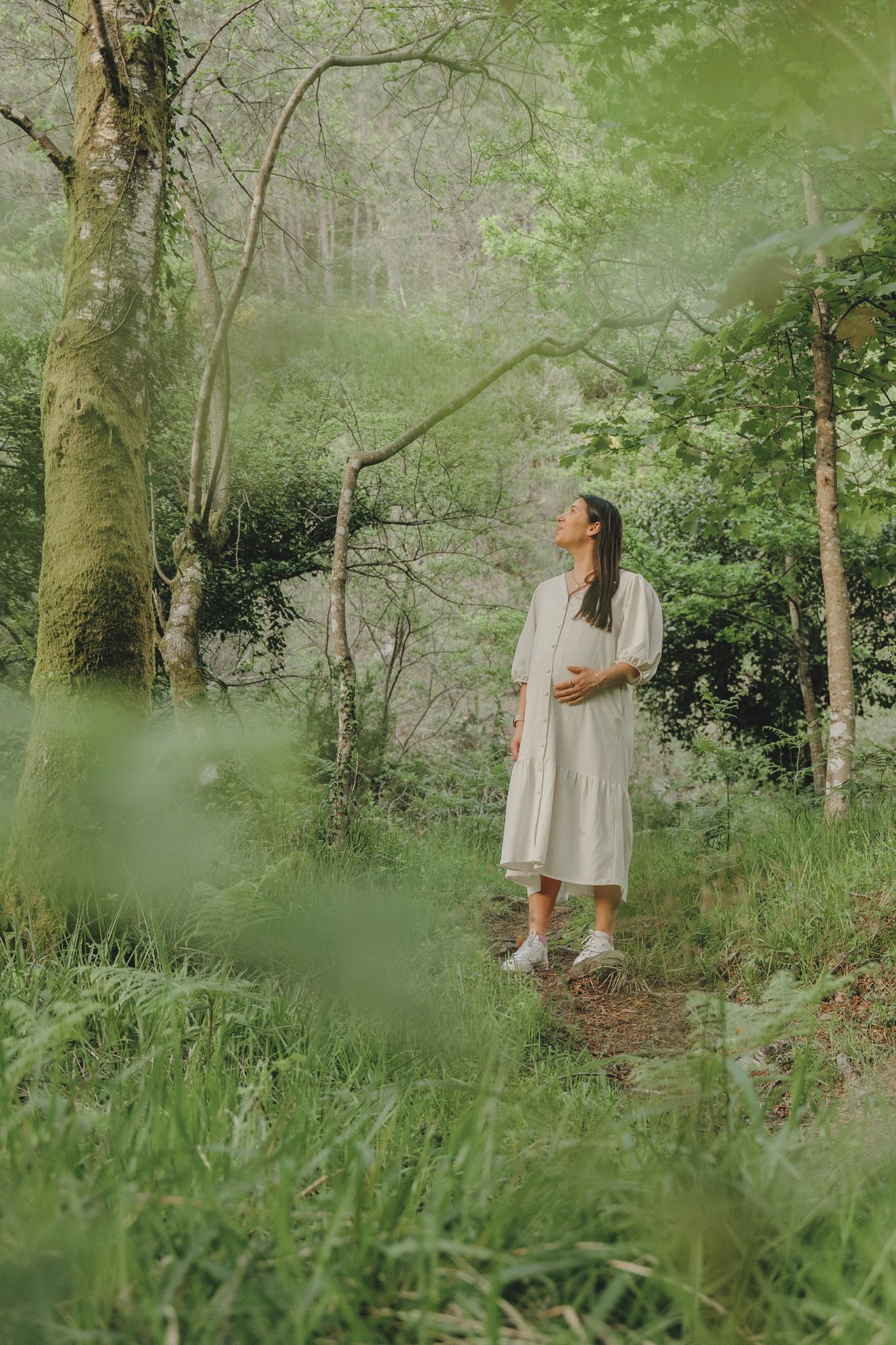 Dreamy forest scene with figures walking among trees and green foliage.