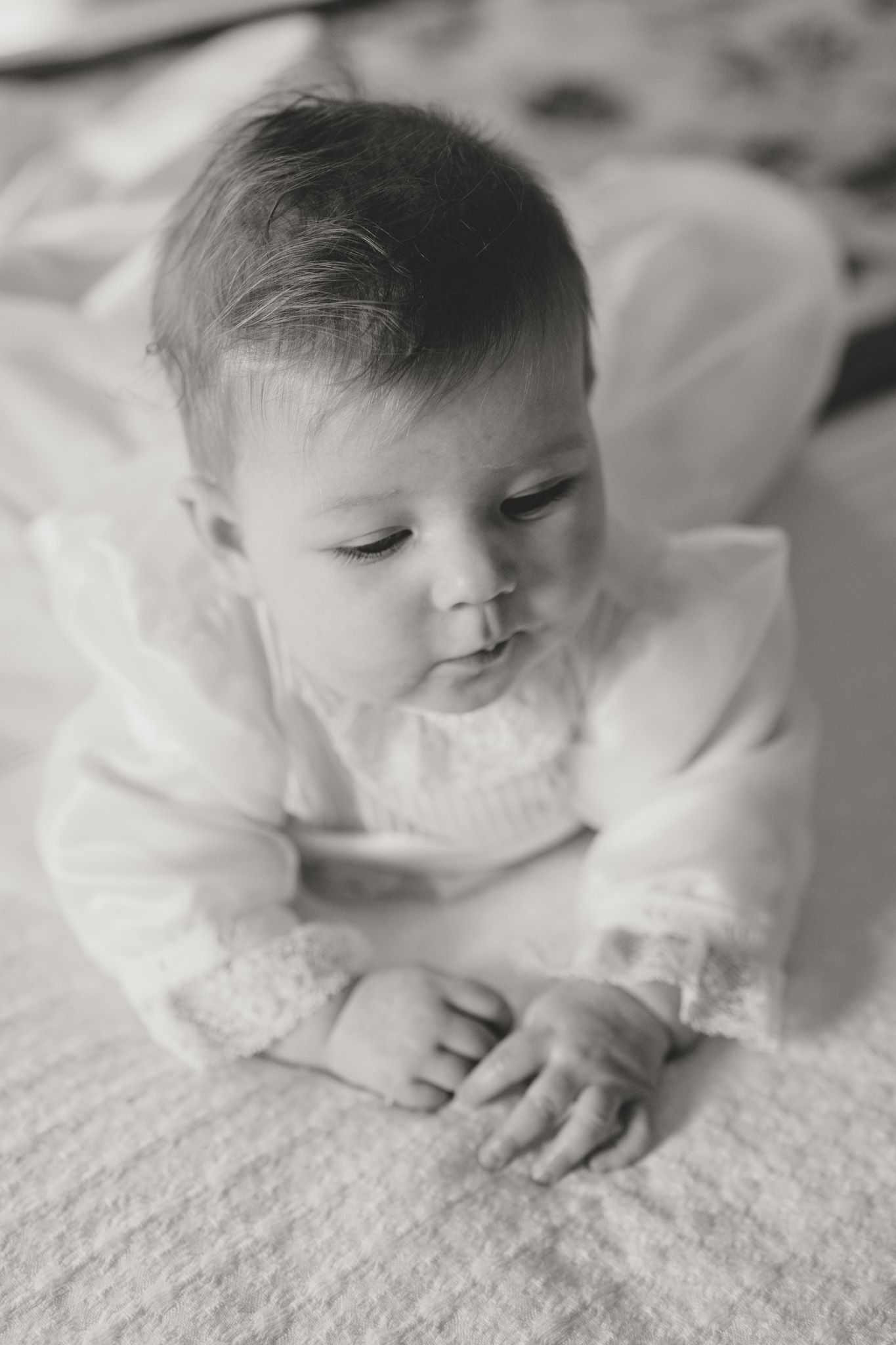 Multiple tender black and white portraits of a baby resting on white bedding.