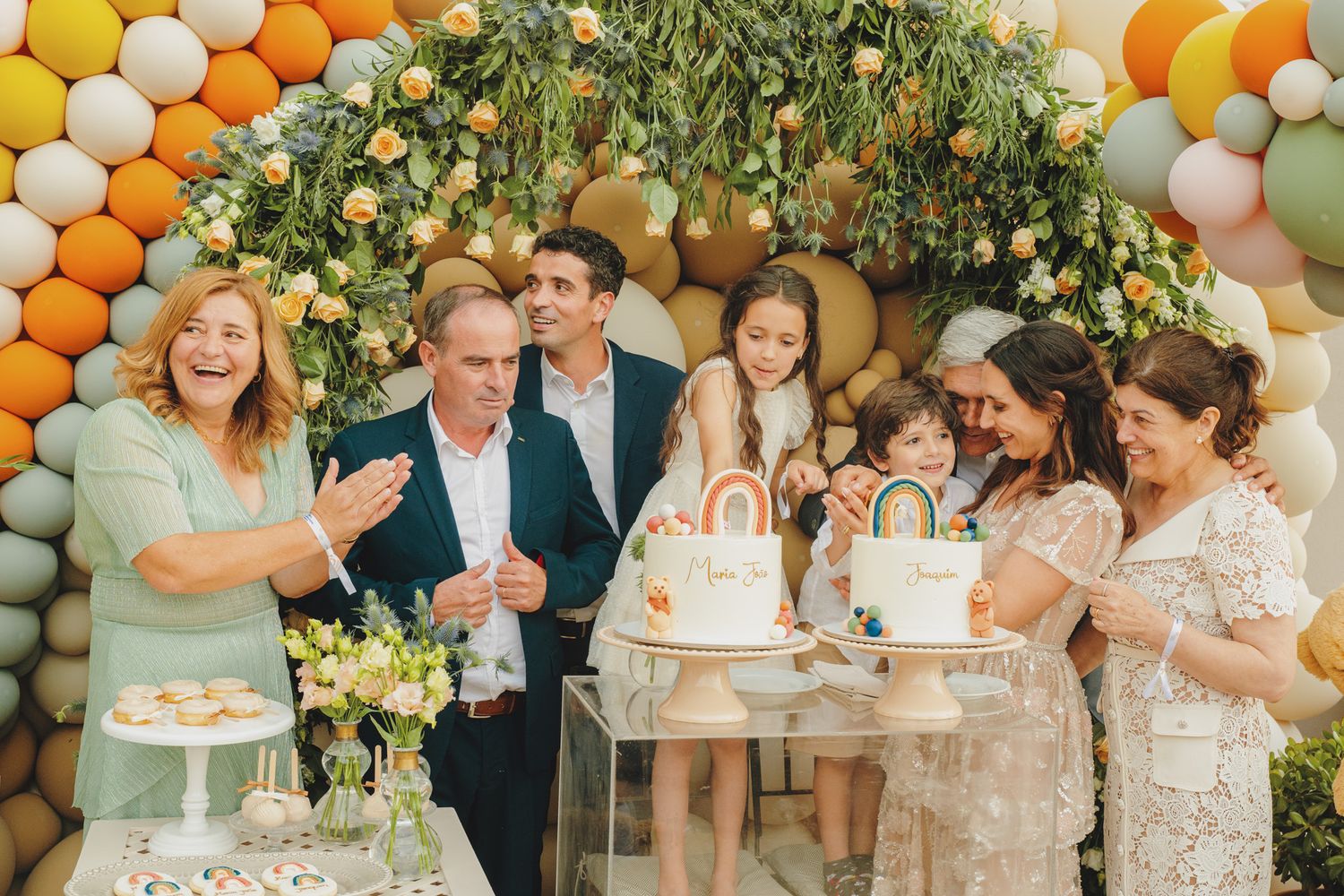 Party guests celebrating around decorated tables with colorful balloon arrangements.