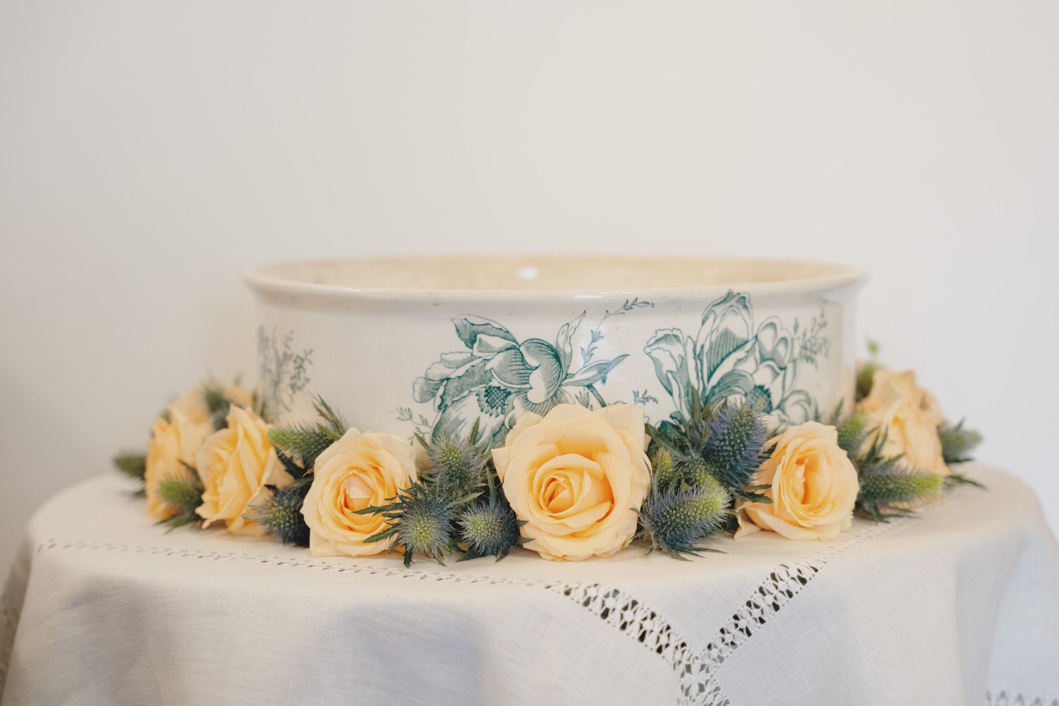 Wedding cake decorated with yellow roses and greenery on a white background.