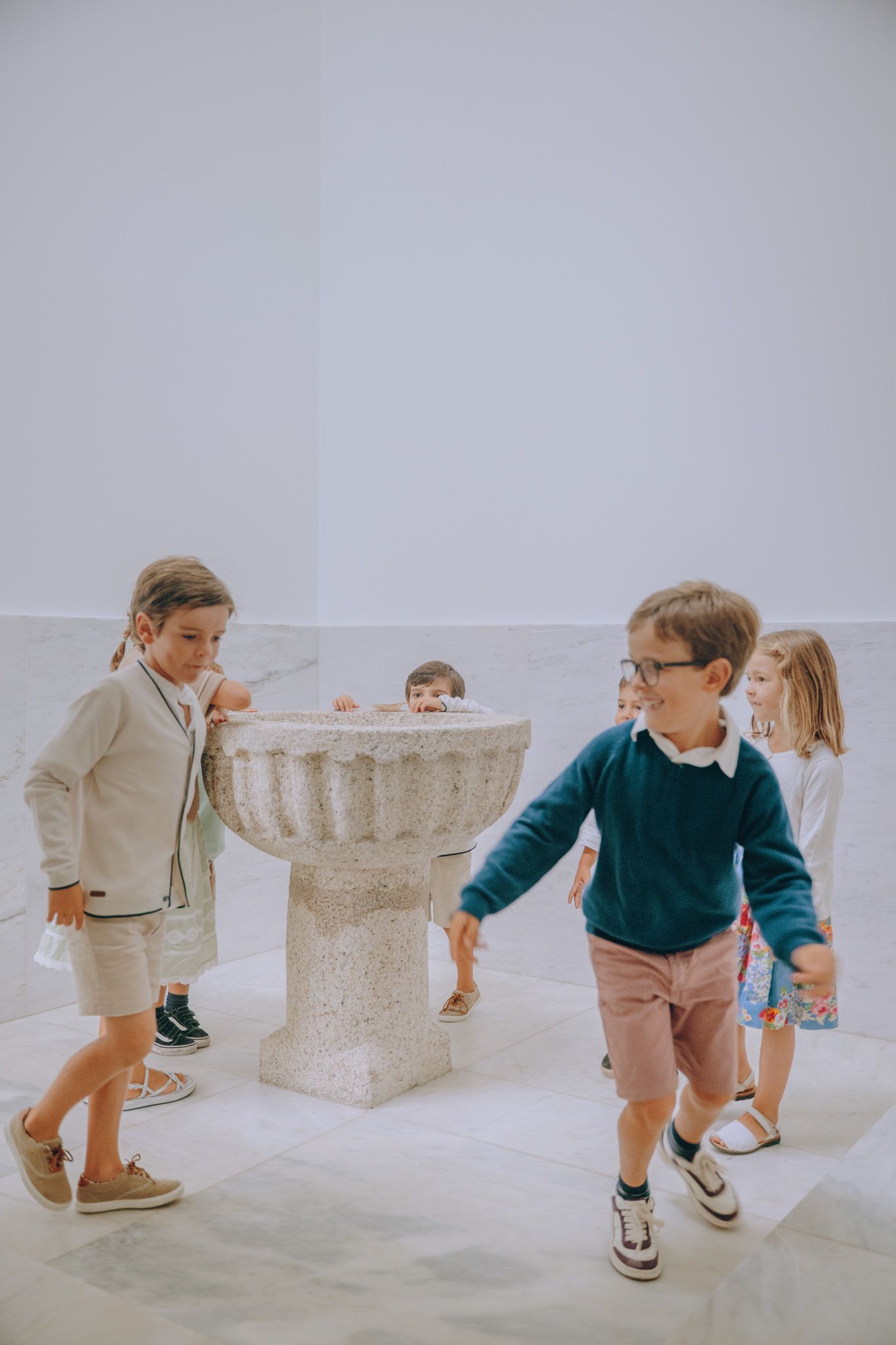 Children playing hide and seek behind white stone blocks in a minimalist setting.