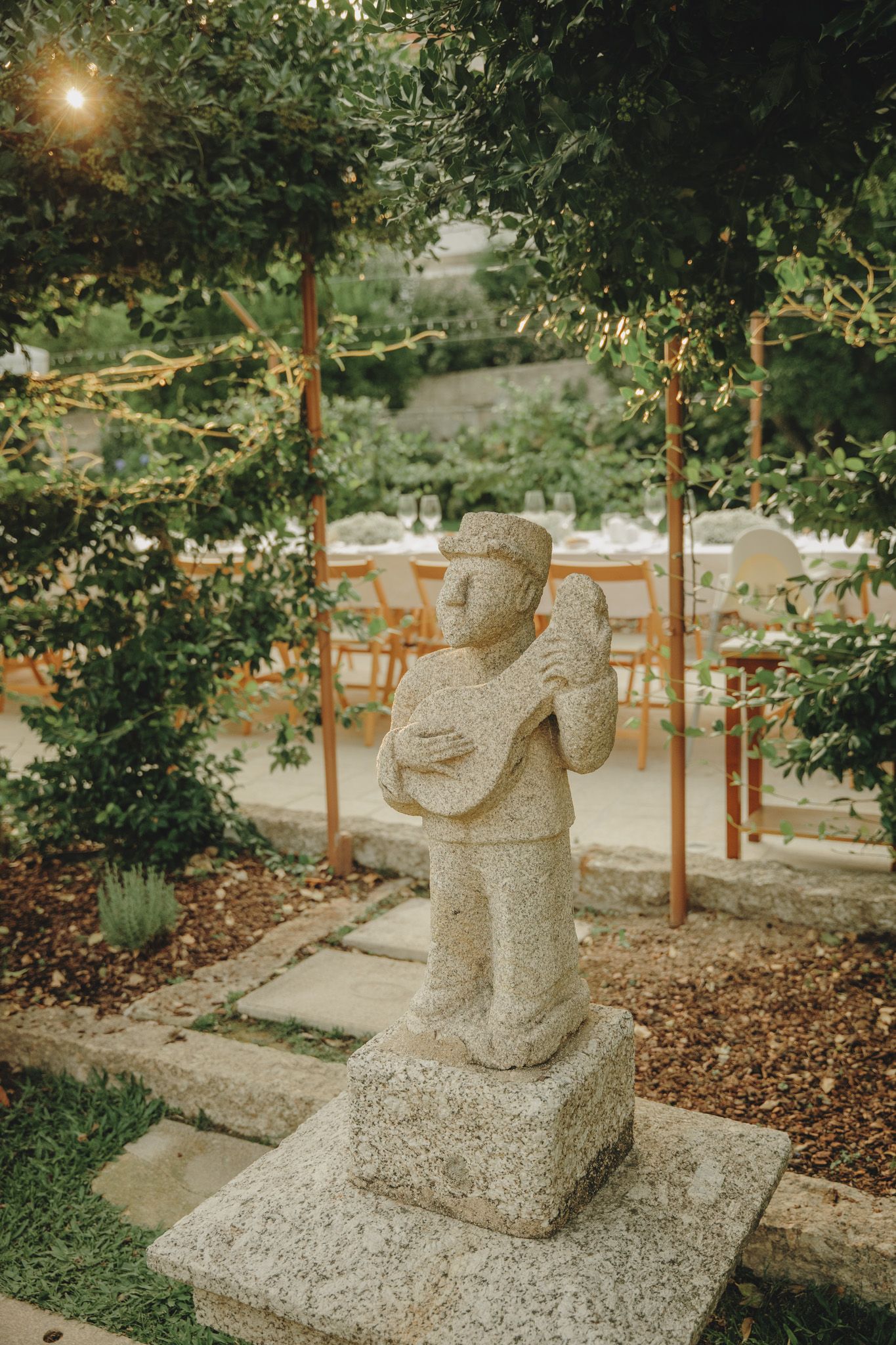 Stone sculptures arranged in a garden path with trees and wooden posts.