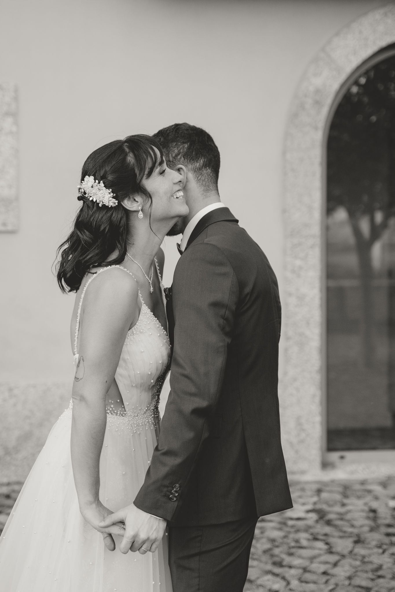 Romantic black and white close-up of wedding couple sharing tender moment against stone wall.