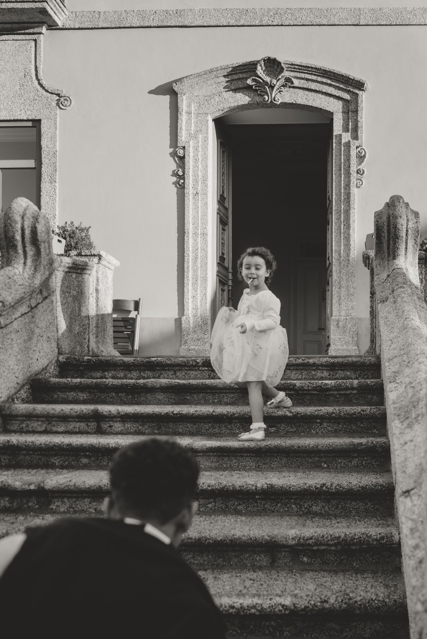 Black and white wedding portrait on stone steps of historic building.