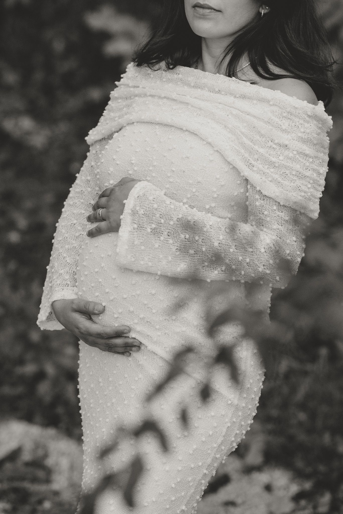 Black and white maternity photo featuring a textured off-shoulder dress with delicate pearl details.