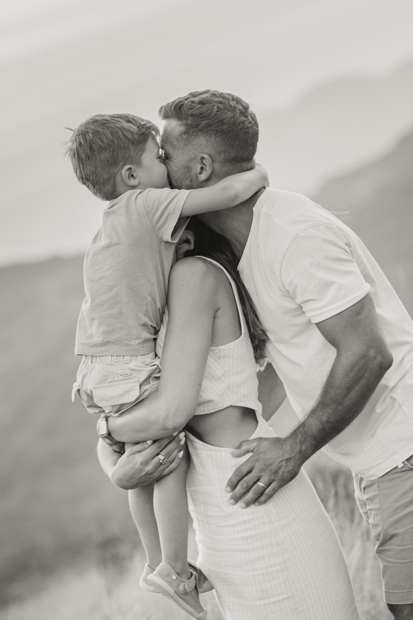 Black and white family portrait showing tender moments of affection outdoors.